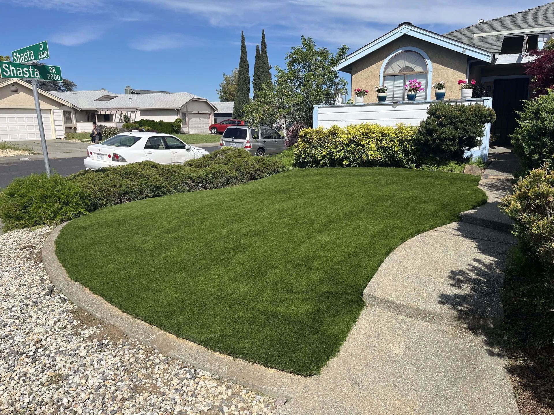 A house with a lush green lawn and a white car parked in front of it.