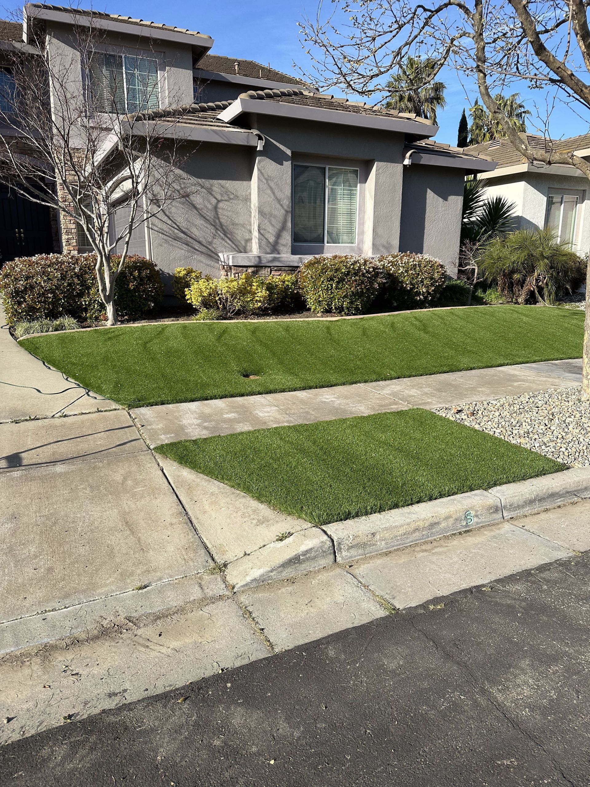 A house with a lush green lawn and a sidewalk in front of it.