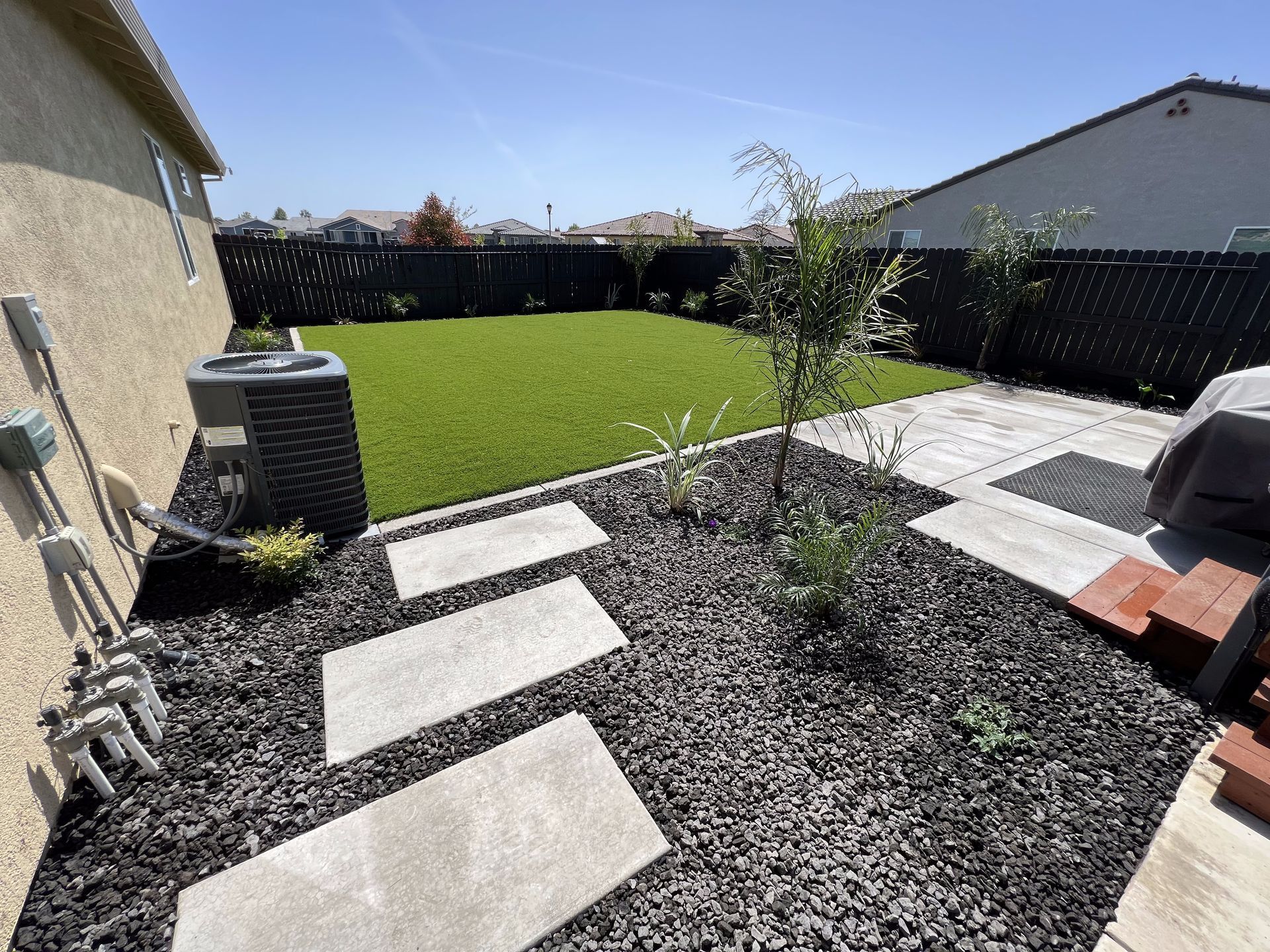 A backyard with a lawn and a walkway leading to it