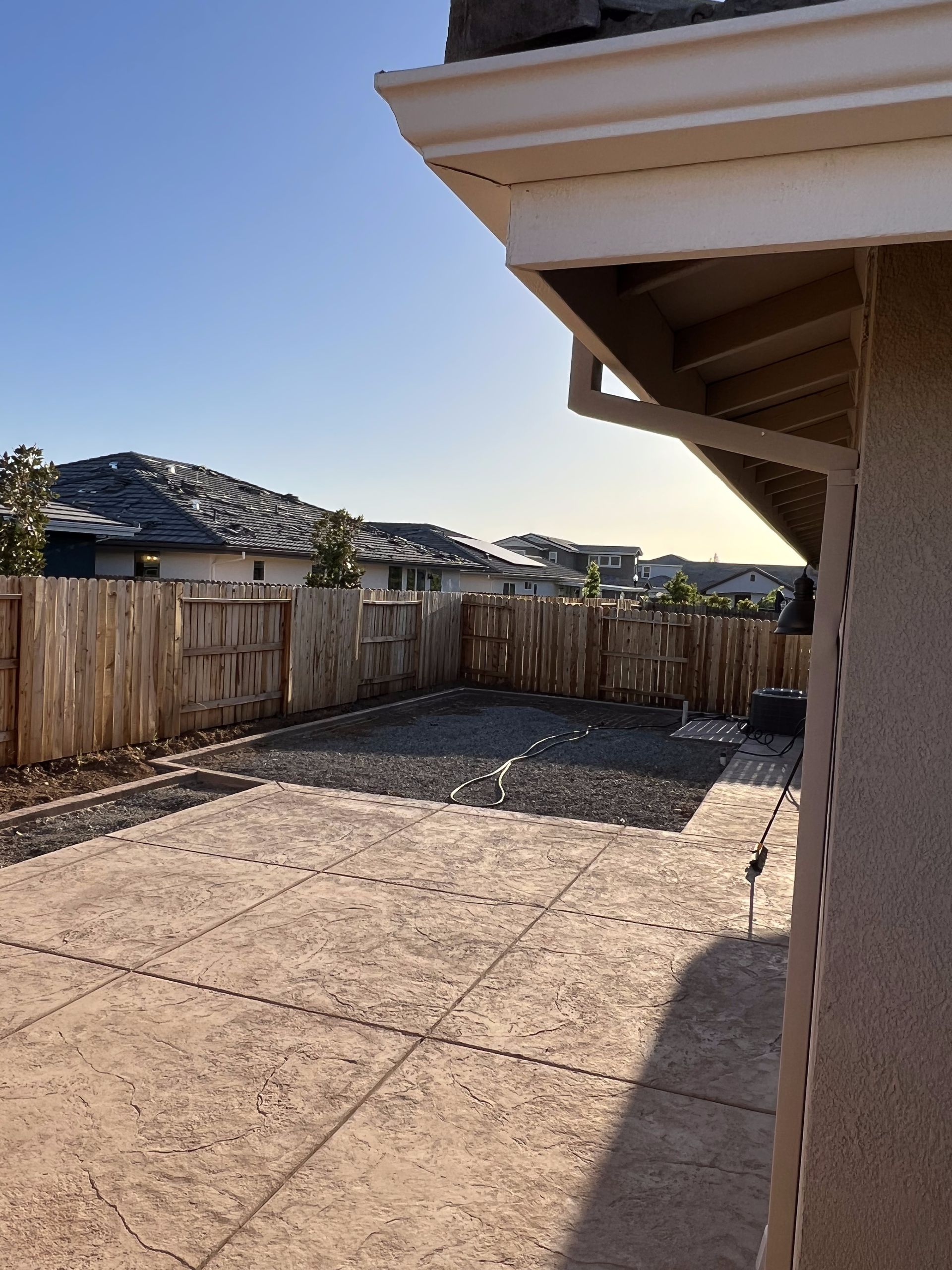 A backyard with a fence and a house in the background