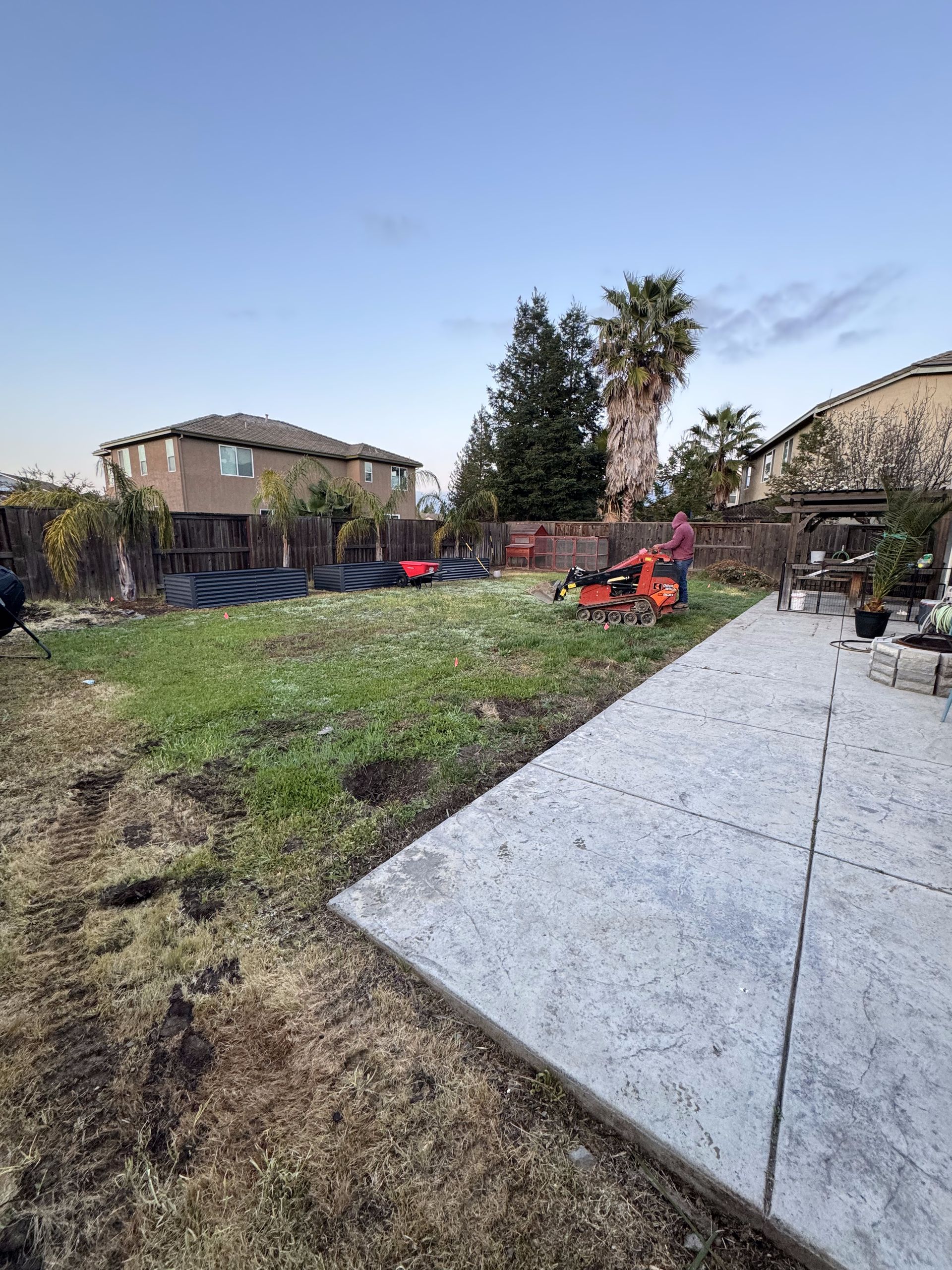 A man is mowing the grass in a backyard with a lawn mower.