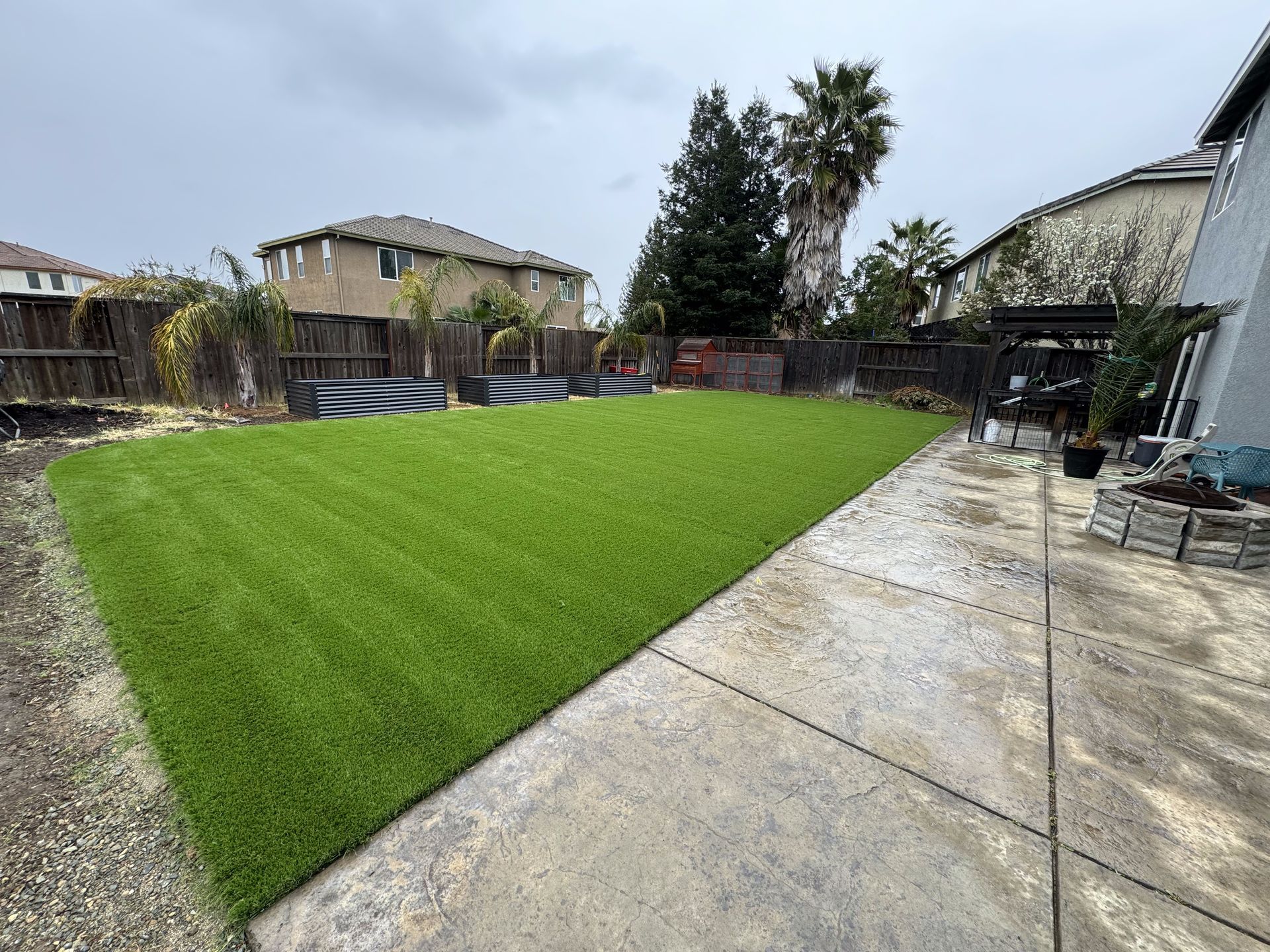 A backyard with a lot of grass and a concrete walkway.