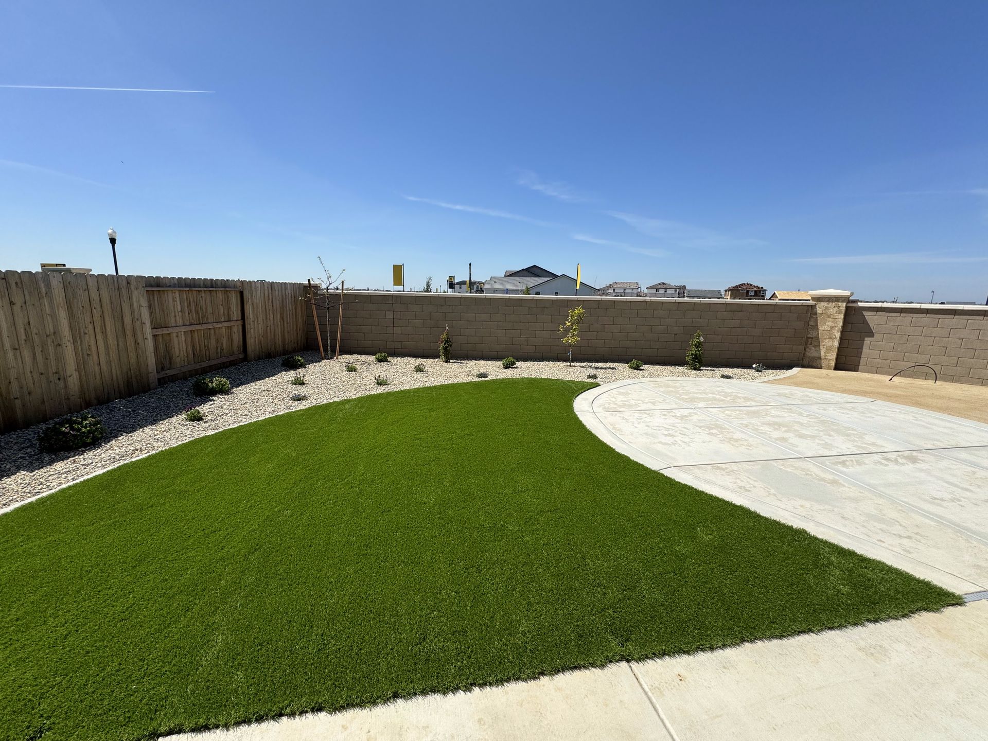 A backyard with a lush green lawn and a concrete walkway.
