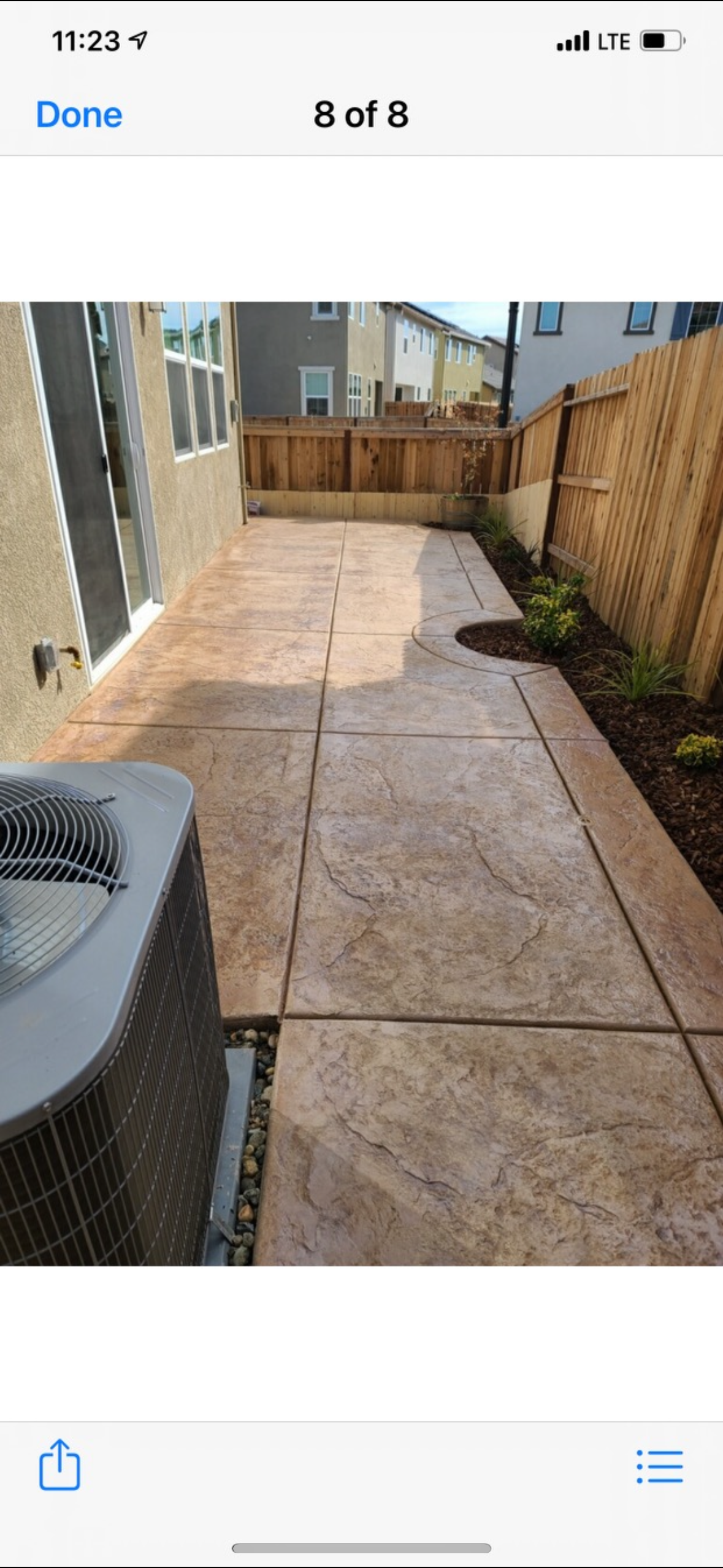 A picture of a patio with a concrete walkway and a fence.