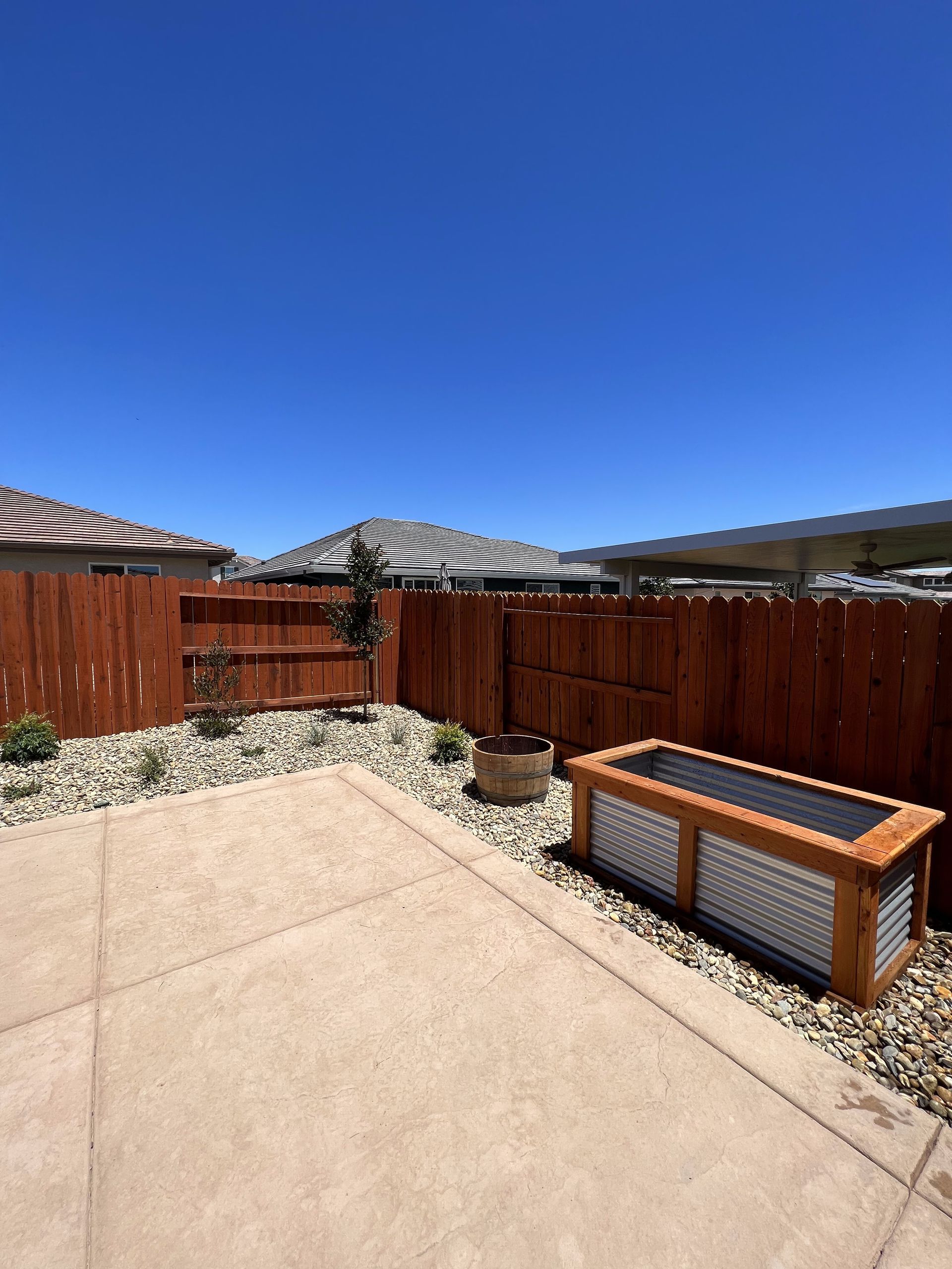 A backyard with a wooden fence and a wooden planter