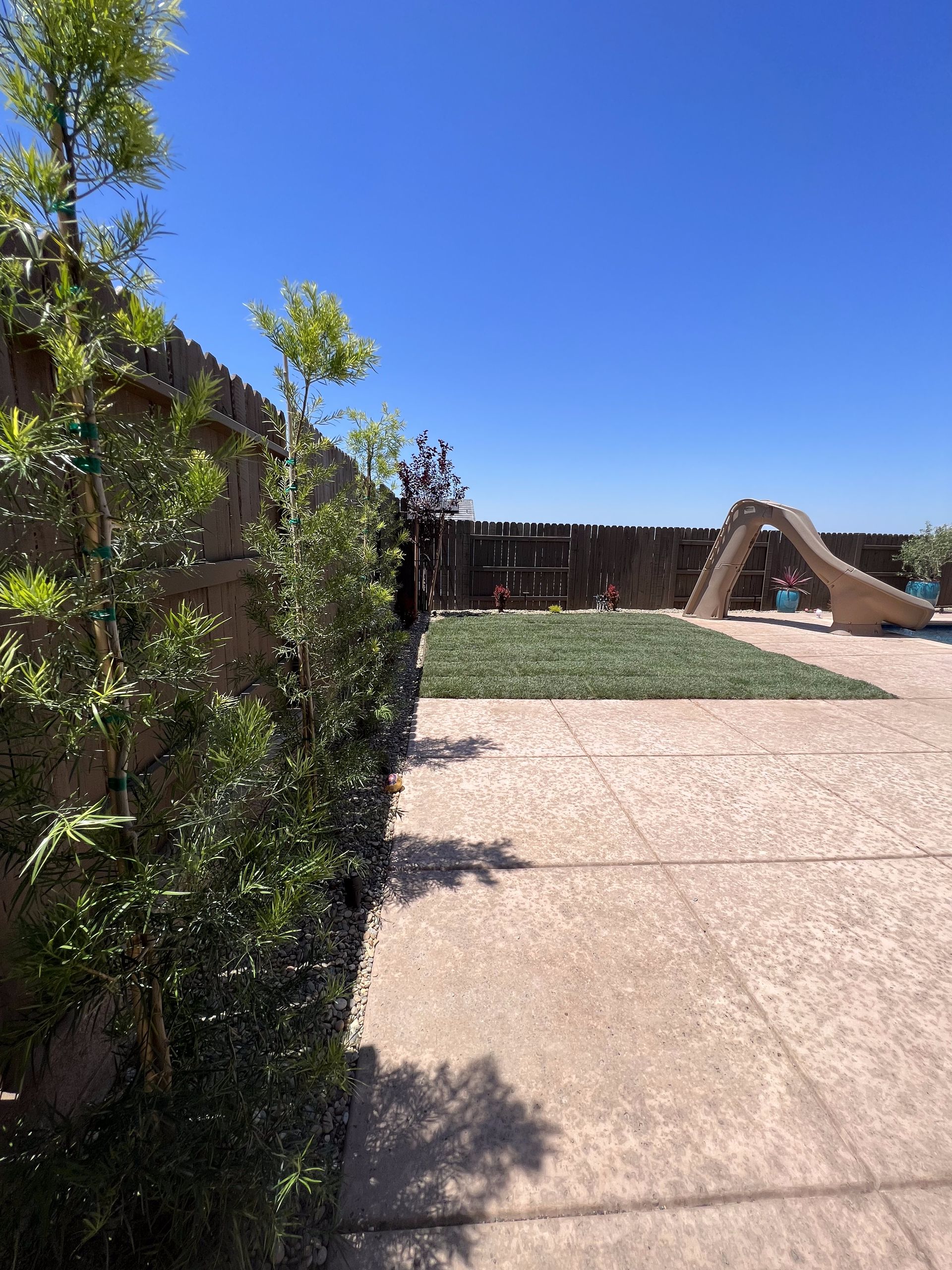 A patio with a slide and a fence in the background