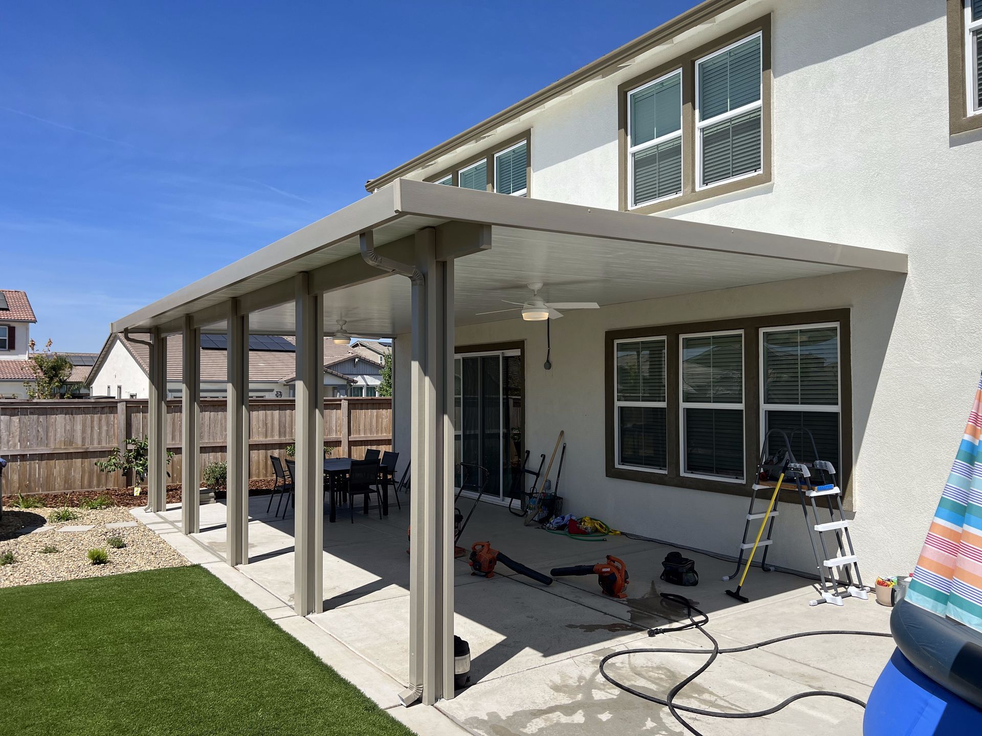 A large white house with a covered patio in front of it.