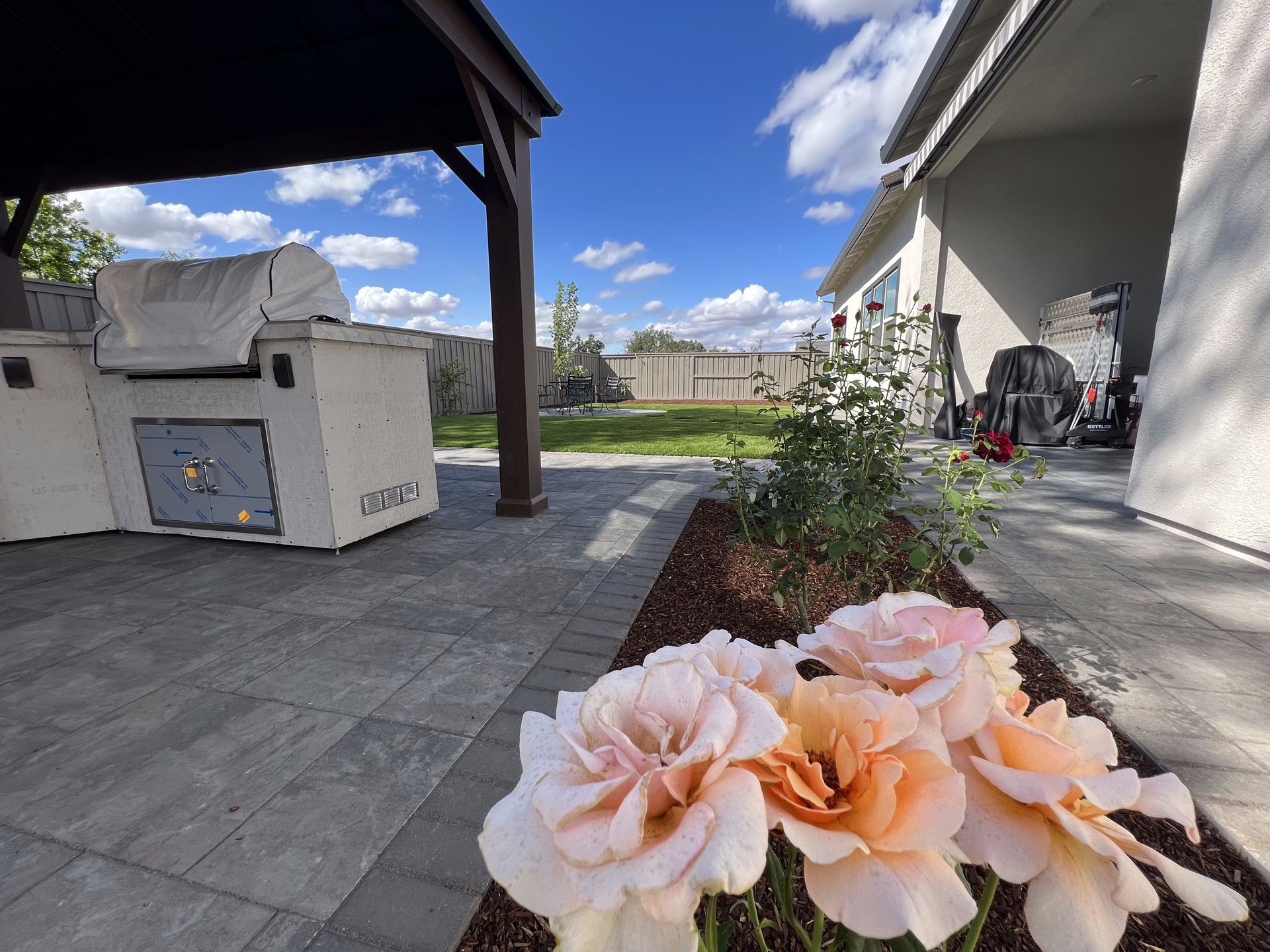 A patio with a grill and flowers in the foreground.