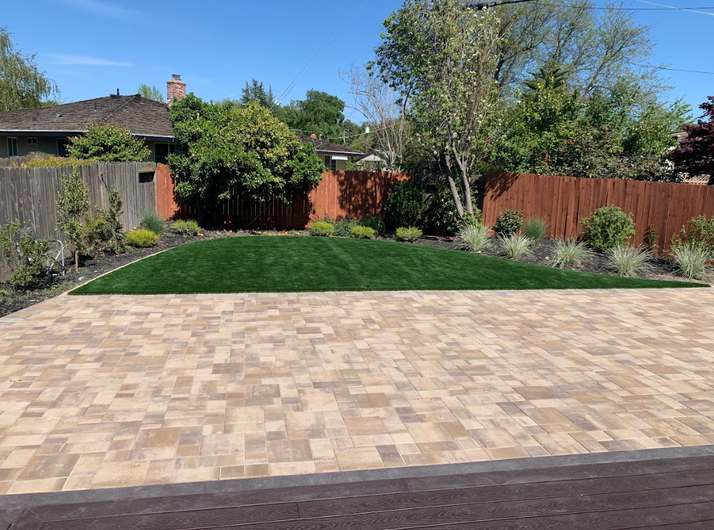 a green lawn next to brown, tan, and red pavers