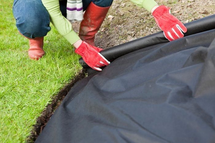 A person wearing red gloves is kneeling down on a black cloth.