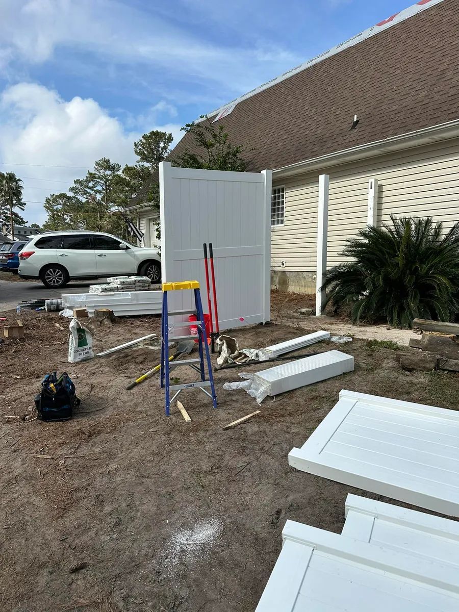 A white fence is being built in front of a house.