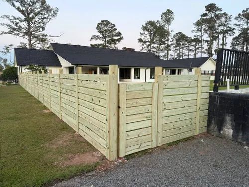 A wooden fence is surrounding a house in a residential area.