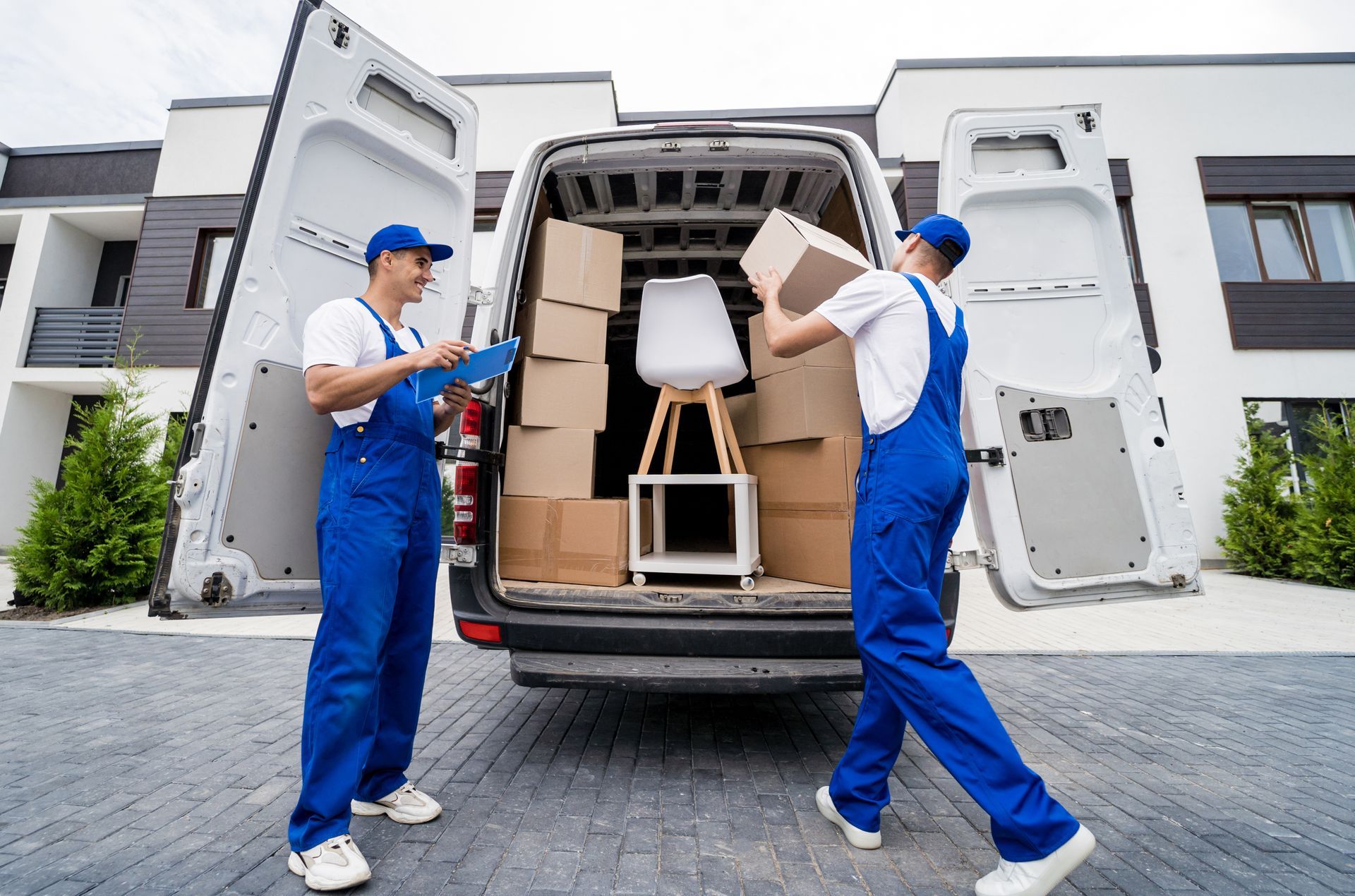 Two men are loading boxes into a van in front of a house.