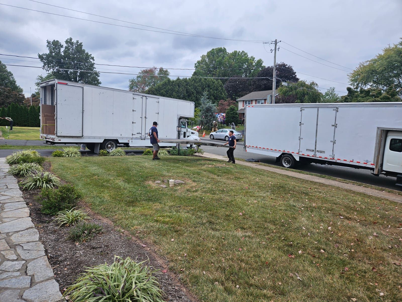 A couple of white trucks are parked in a grassy field.