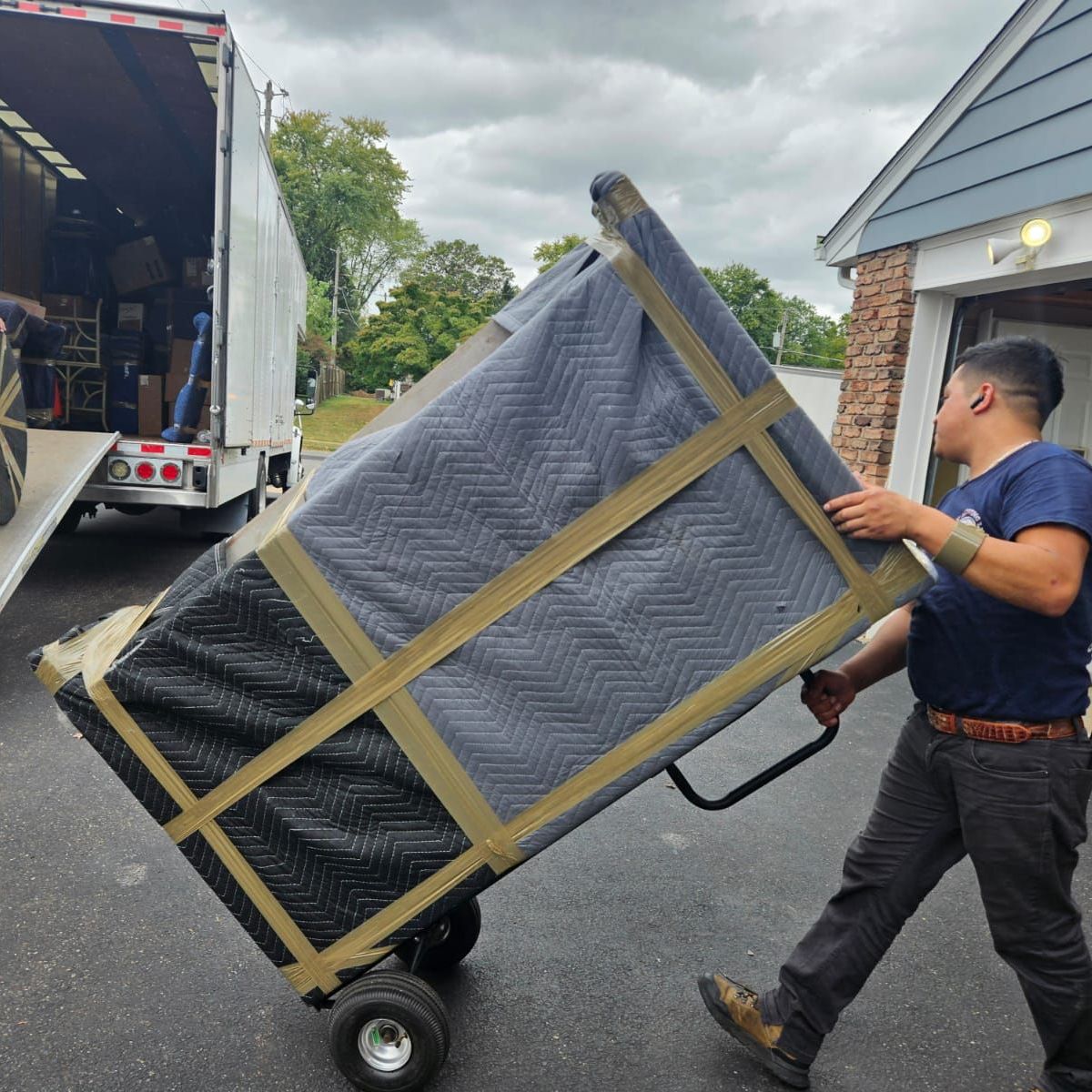 A man is pushing a large piece of furniture on a cart