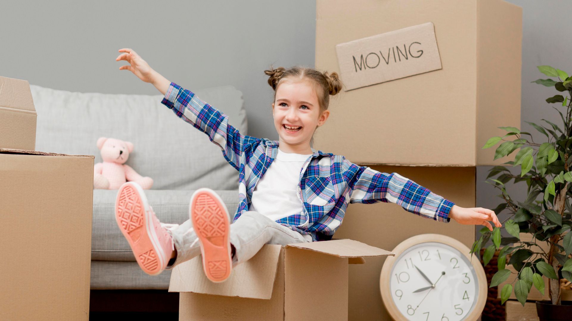 A little girl is sitting in a cardboard box.