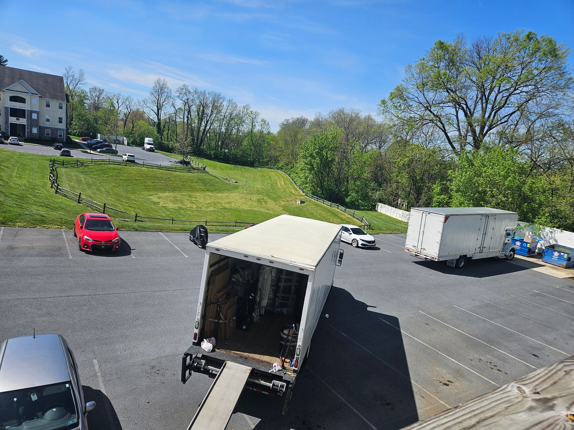 A red car is parked next to a white truck in a parking lot.