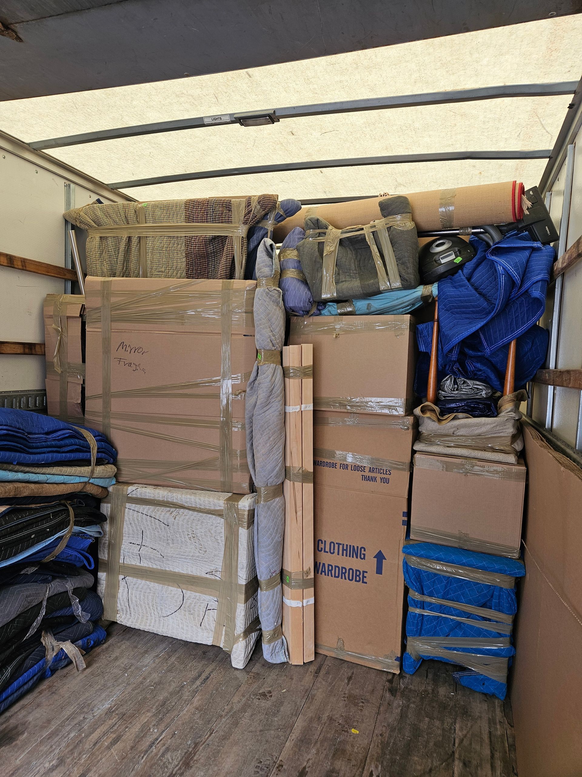 A moving truck filled with lots of boxes and blankets.