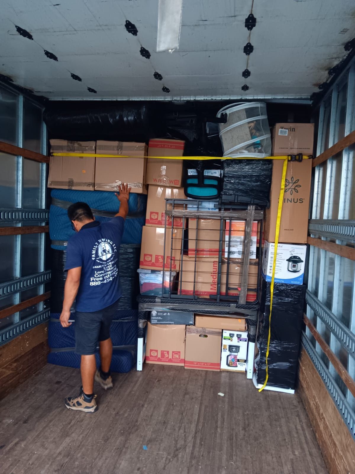 A man in a blue shirt is measuring boxes in a truck