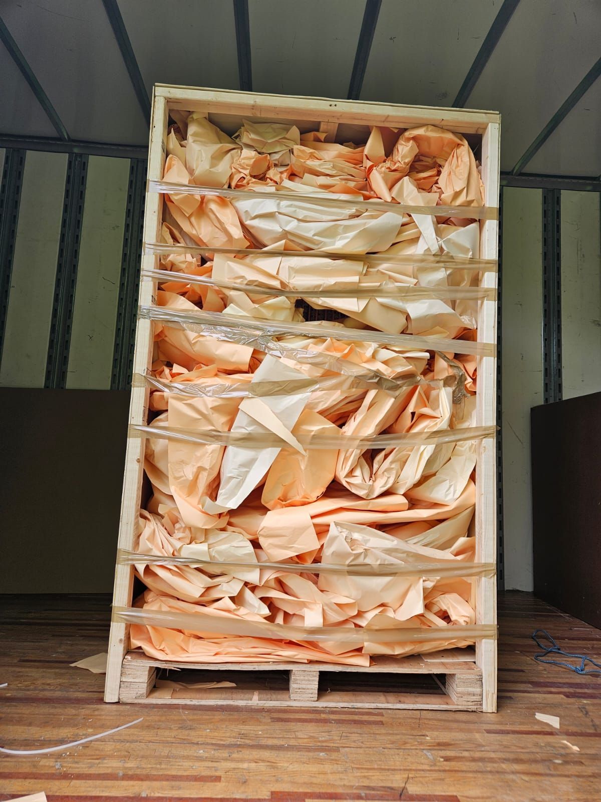 A large wooden crate filled with lots of papers is sitting on a wooden floor.