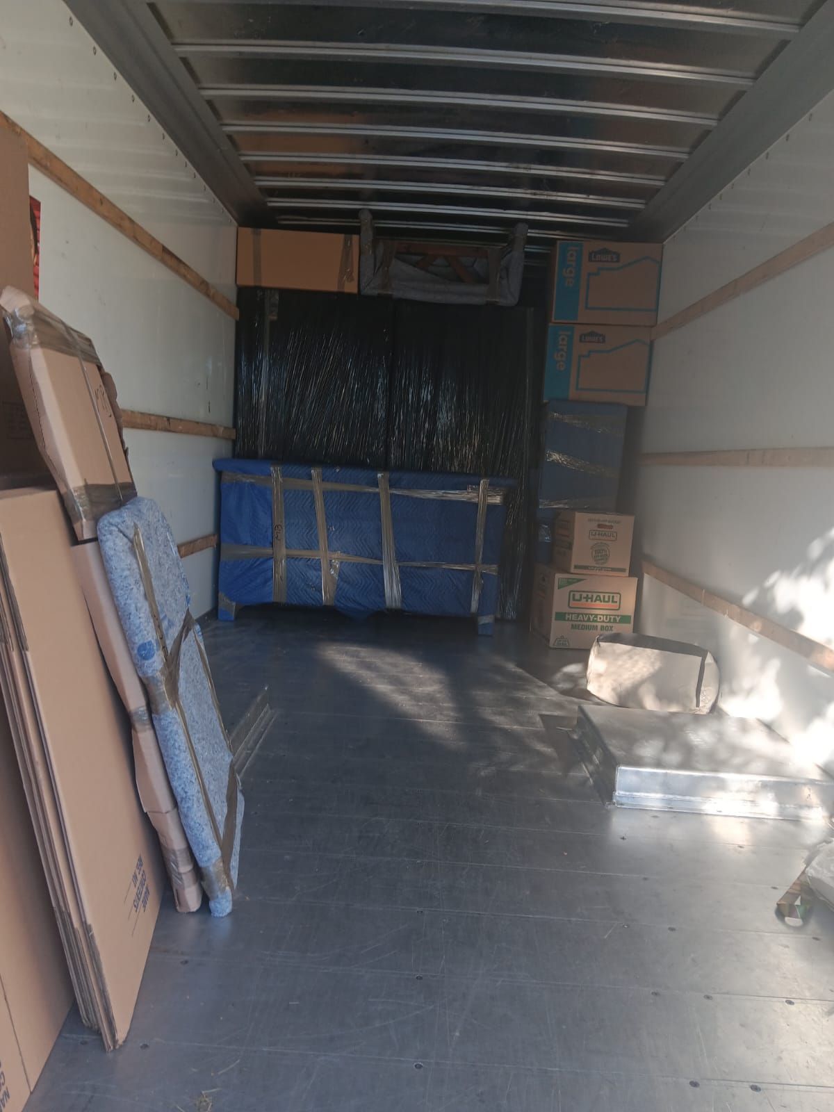 The inside of a moving truck filled with boxes and cardboard boxes.