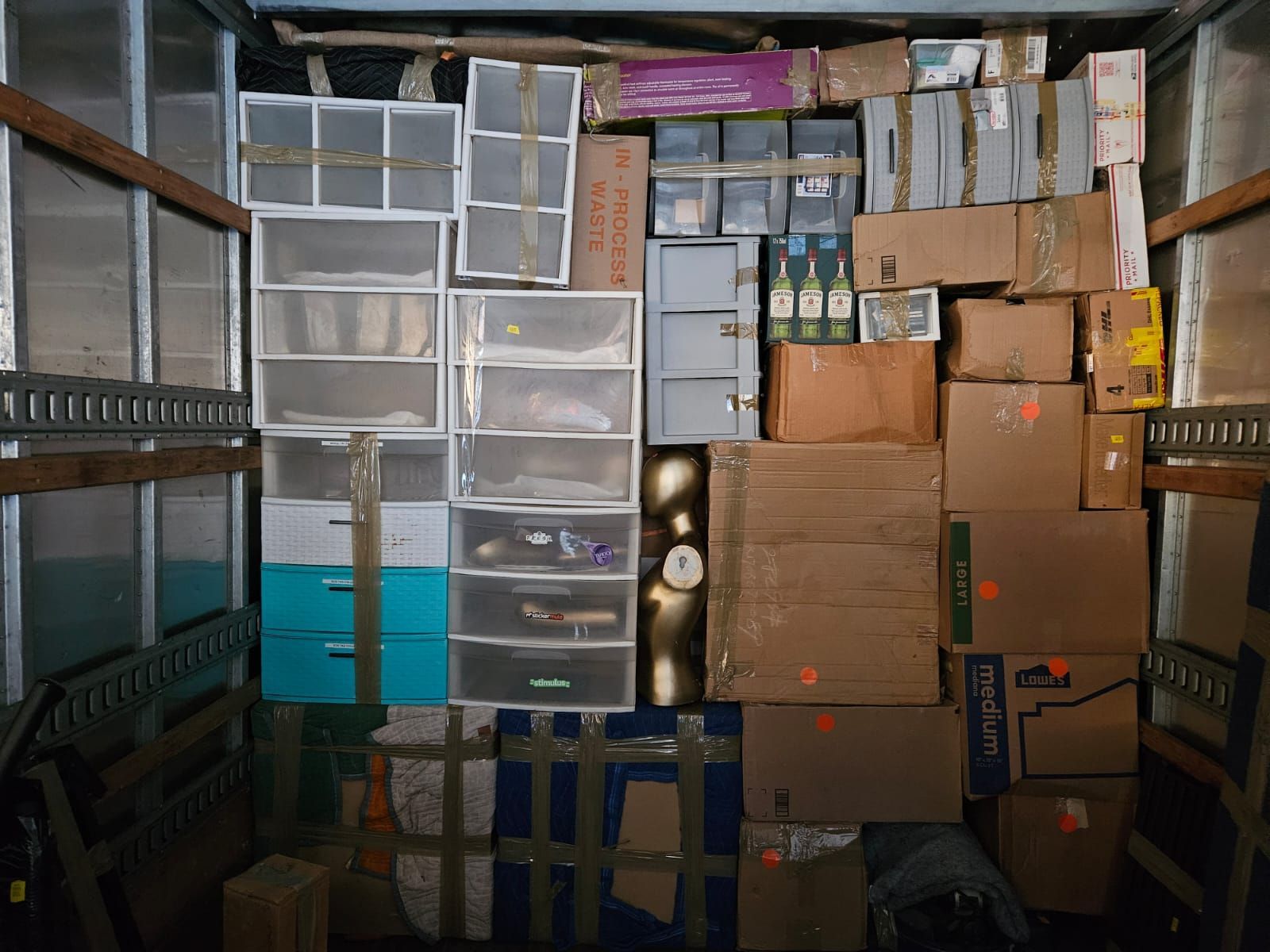The inside of a moving truck filled with boxes and drawers.