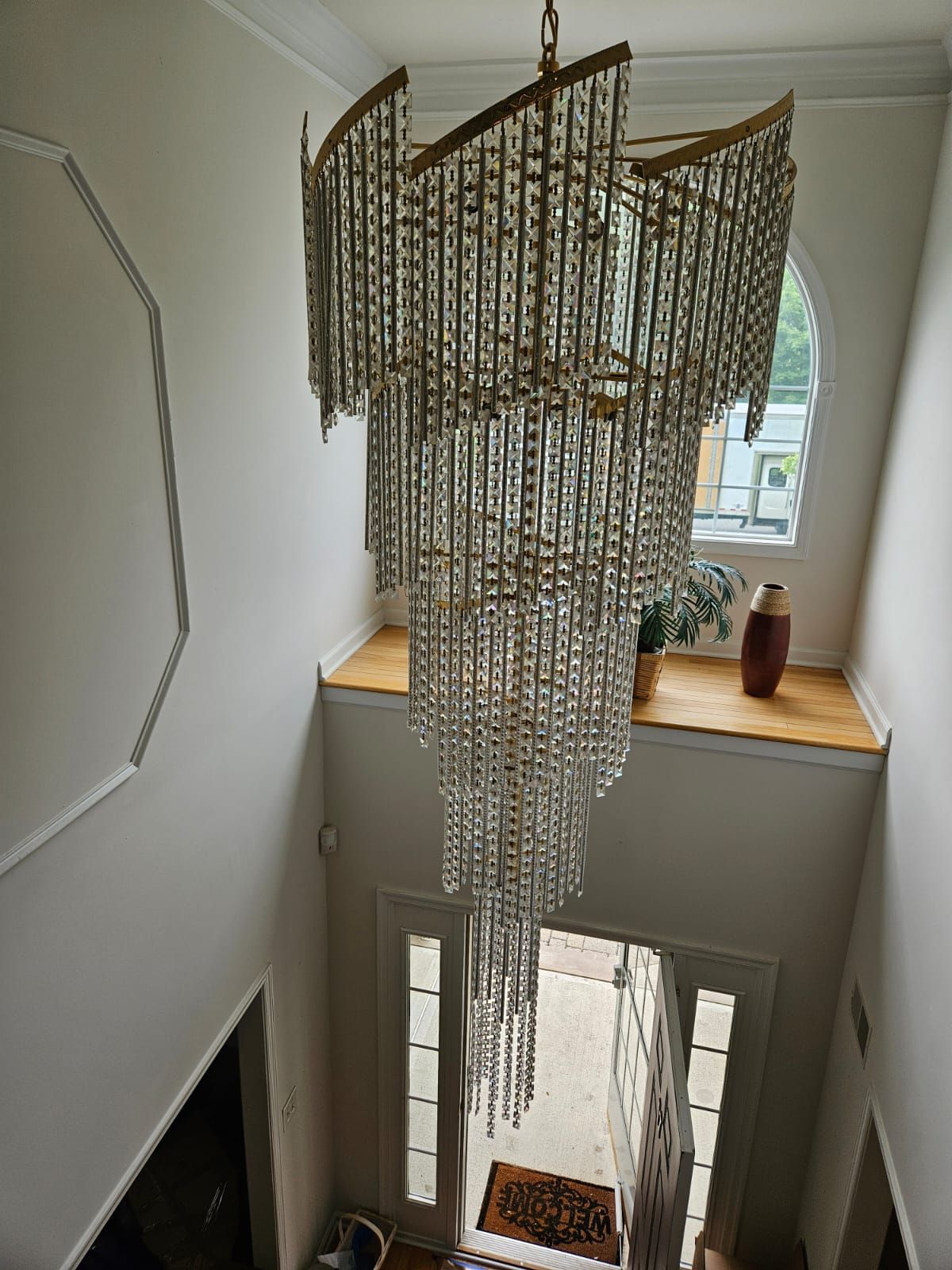A large chandelier is hanging from the ceiling in a hallway.