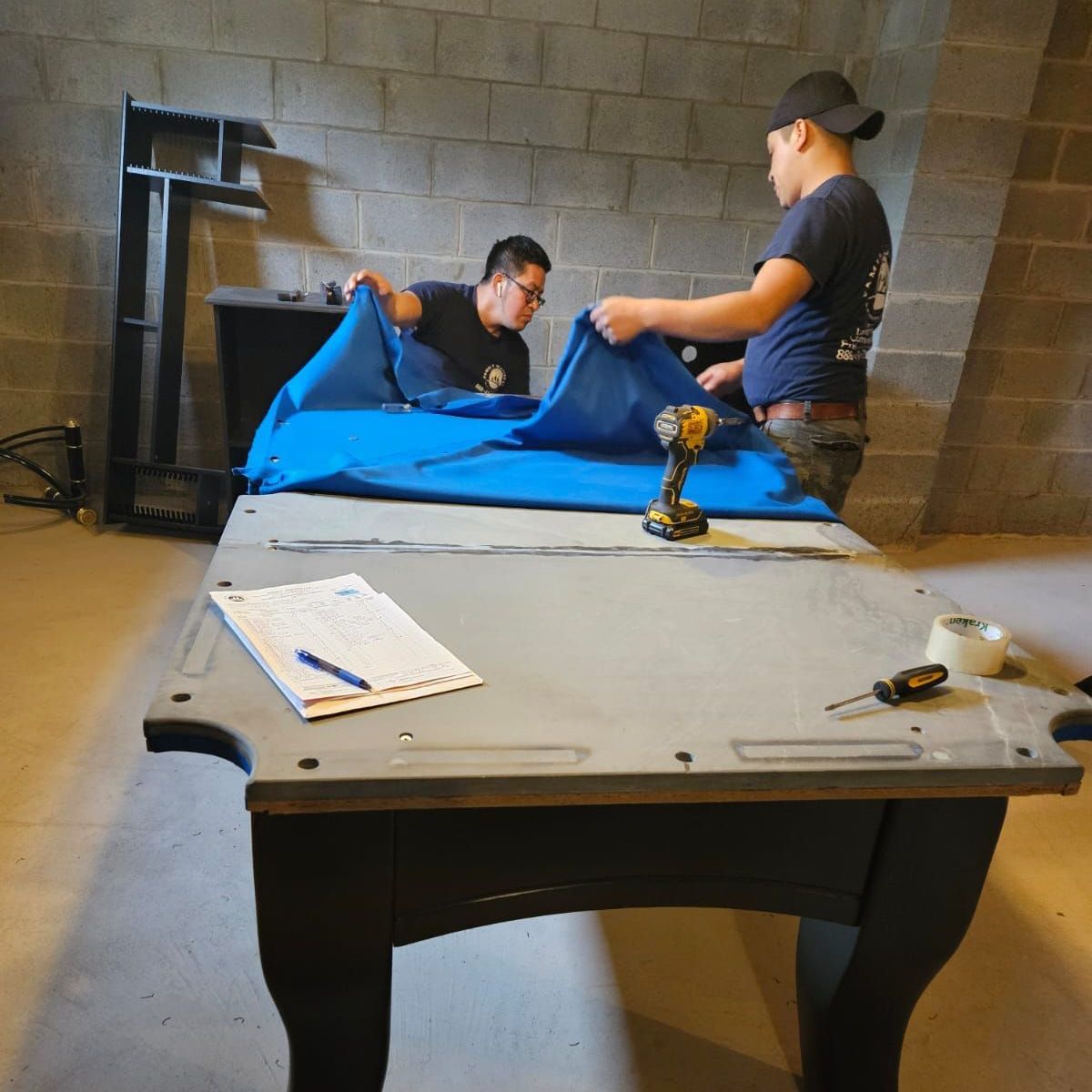 Two men are working on a pool table in a room