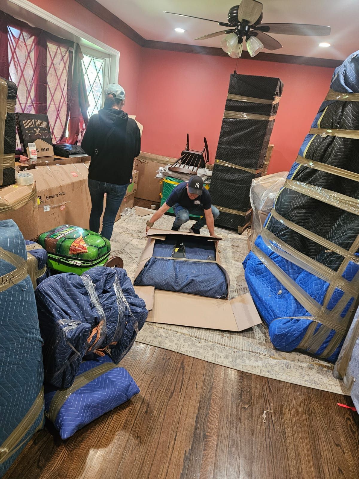 A man is packing a suitcase in a living room.