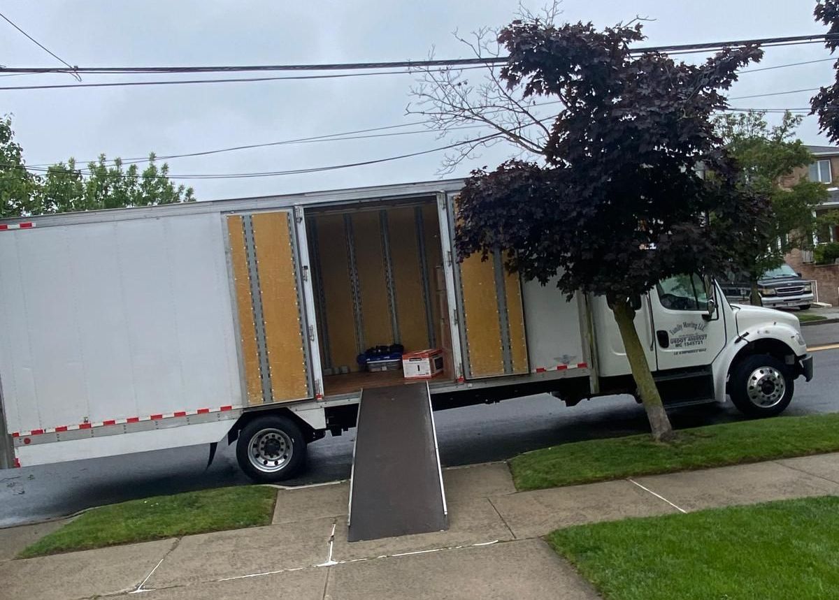 A moving truck is parked on the side of the road with its doors open.
