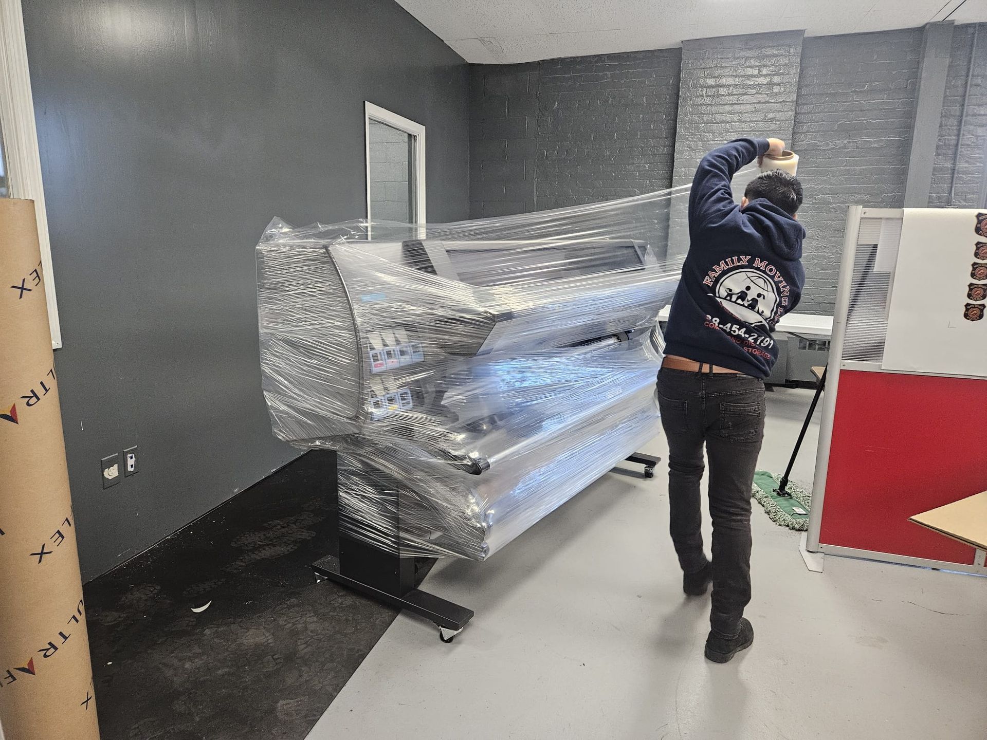 A man is carrying a large piece of plastic in a room.