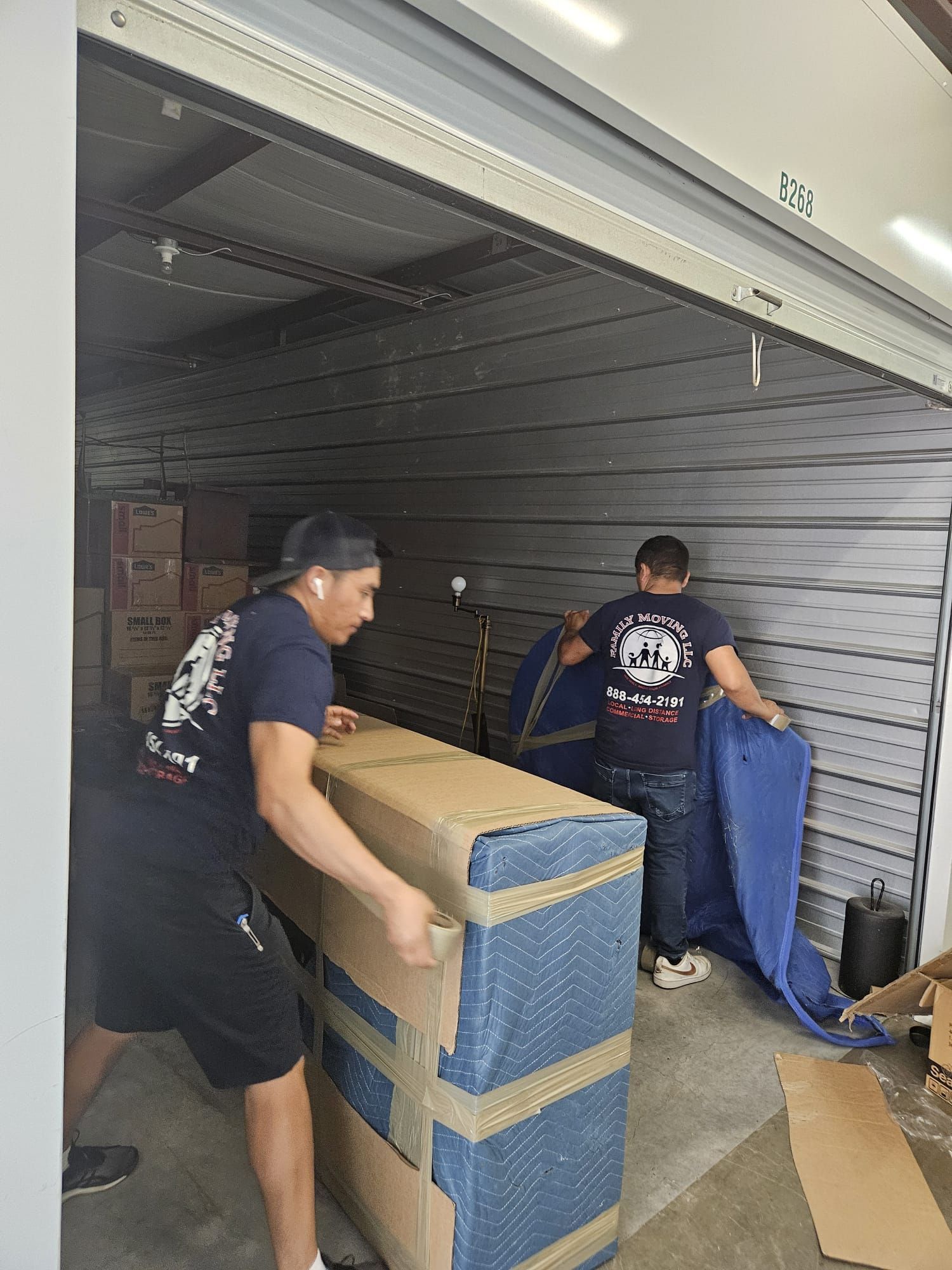 Two men are moving a large box in a garage.