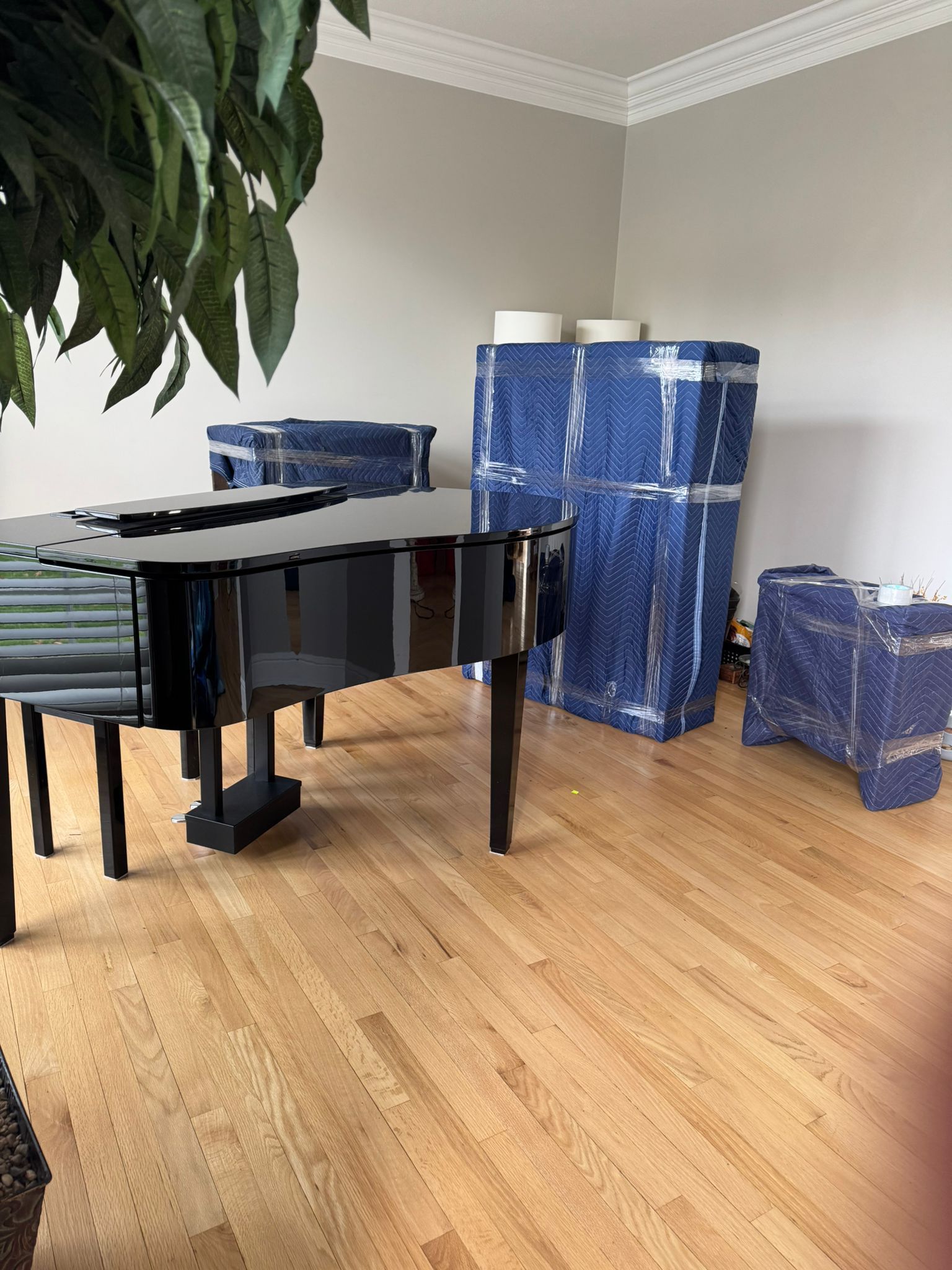 A piano is sitting in a living room surrounded by blue boxes.