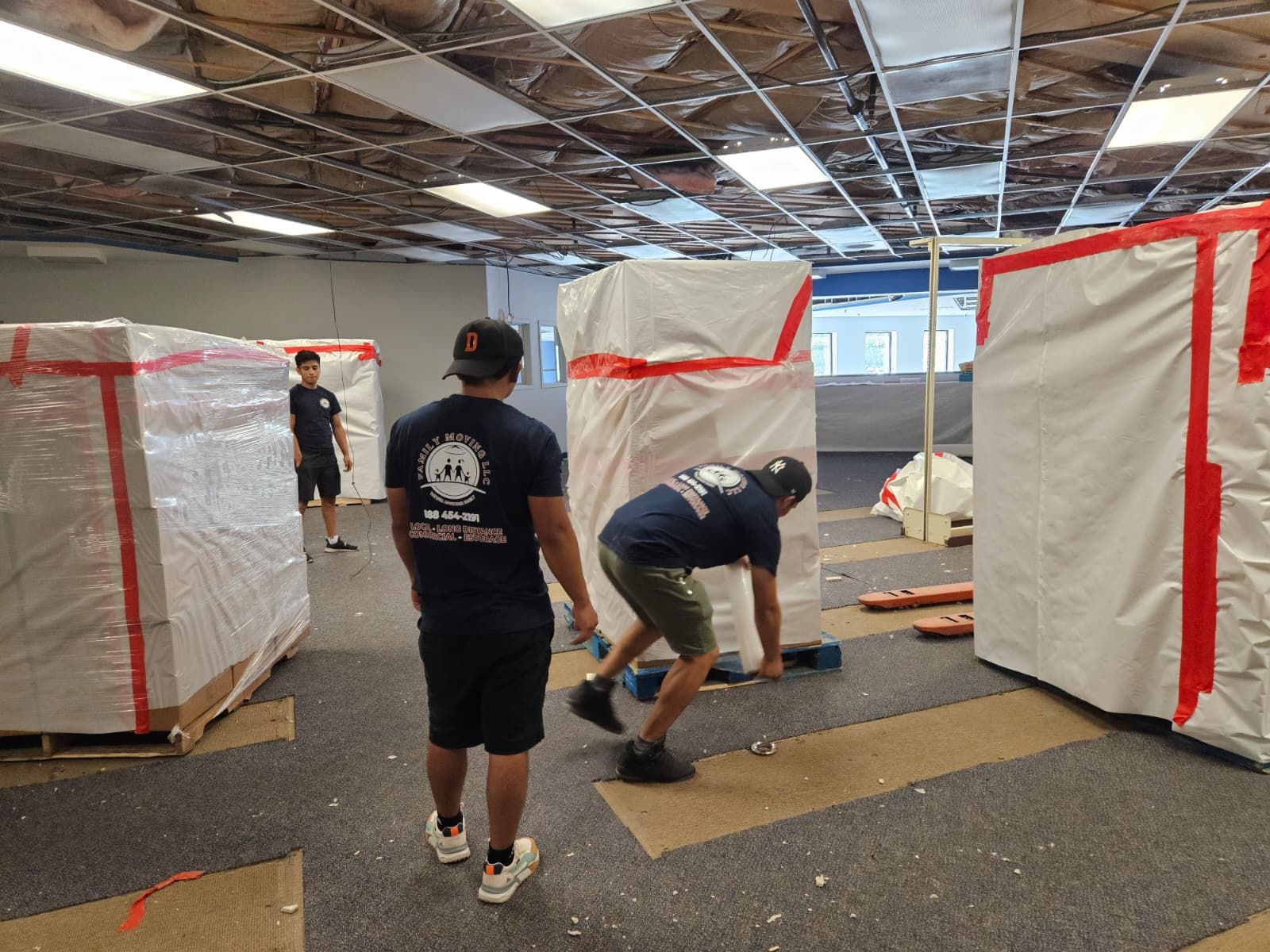 Two men are moving boxes in an office.