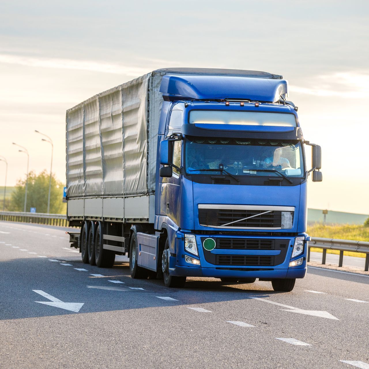 A blue semi truck is driving down a highway.