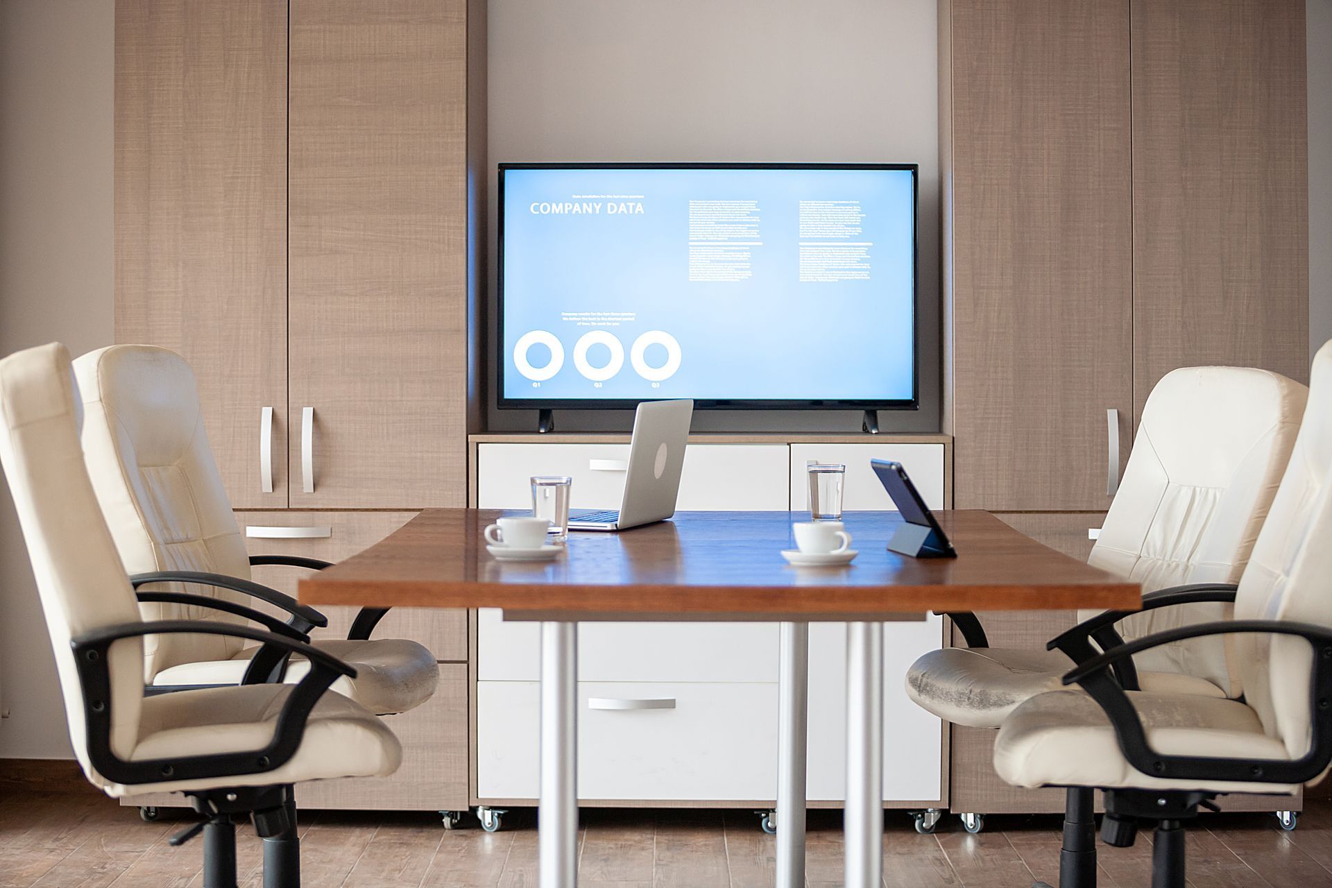 A conference room with a table and chairs and a flat screen tv.