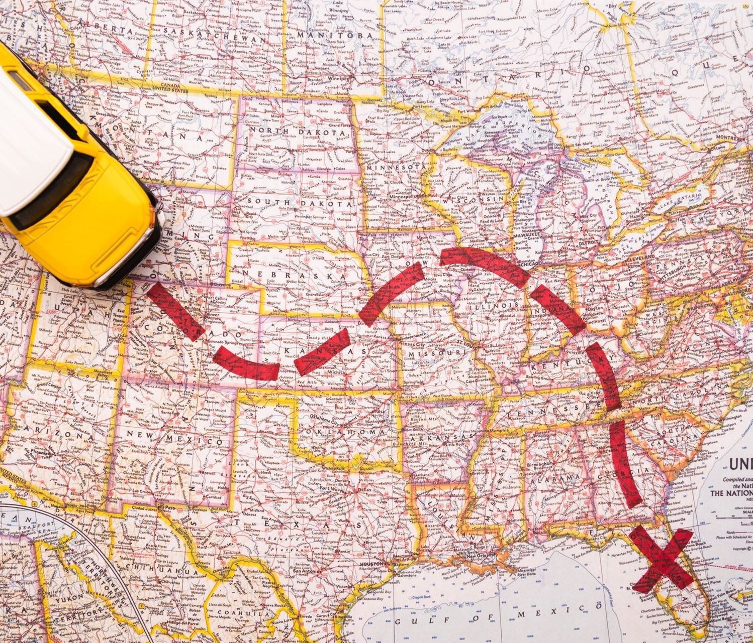 A yellow toy car is driving on a map of the united states.