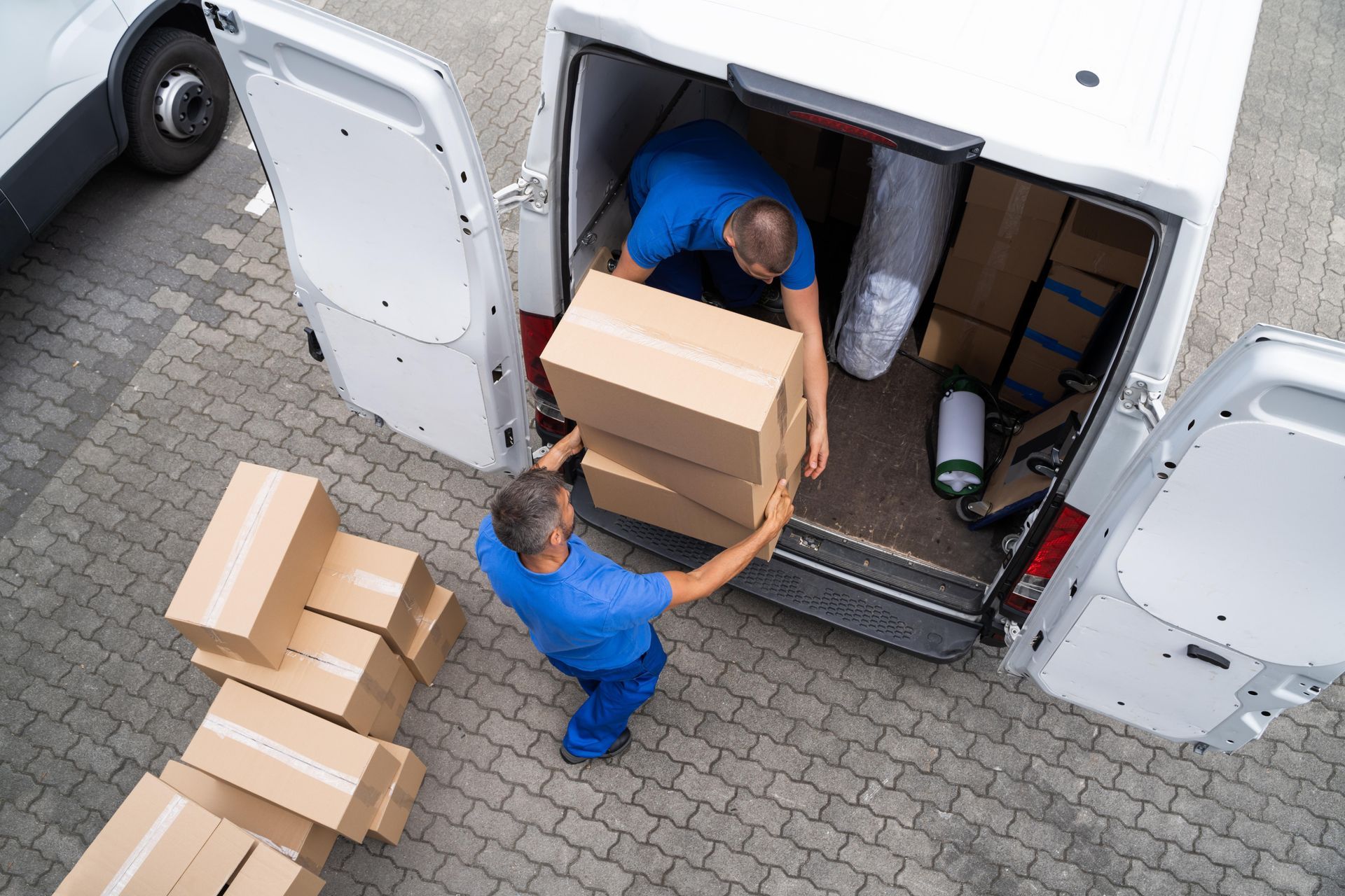 Two men are loading boxes into a van.