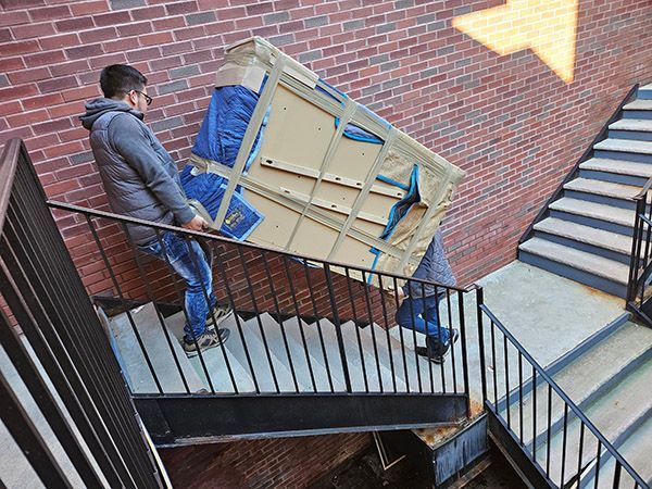 A man is carrying a piano up a set of stairs.