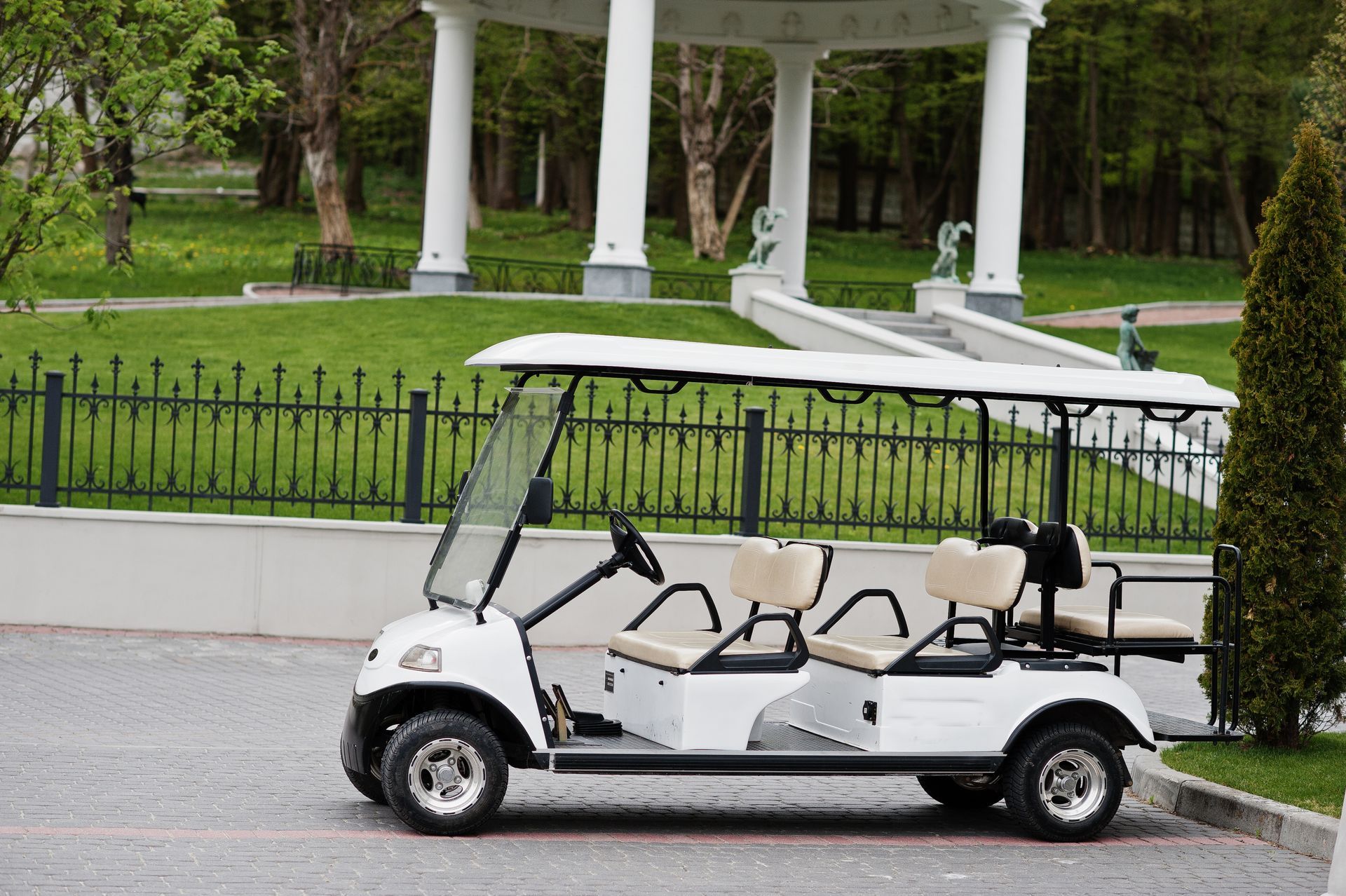 A white golf cart is parked in front of a gazebo