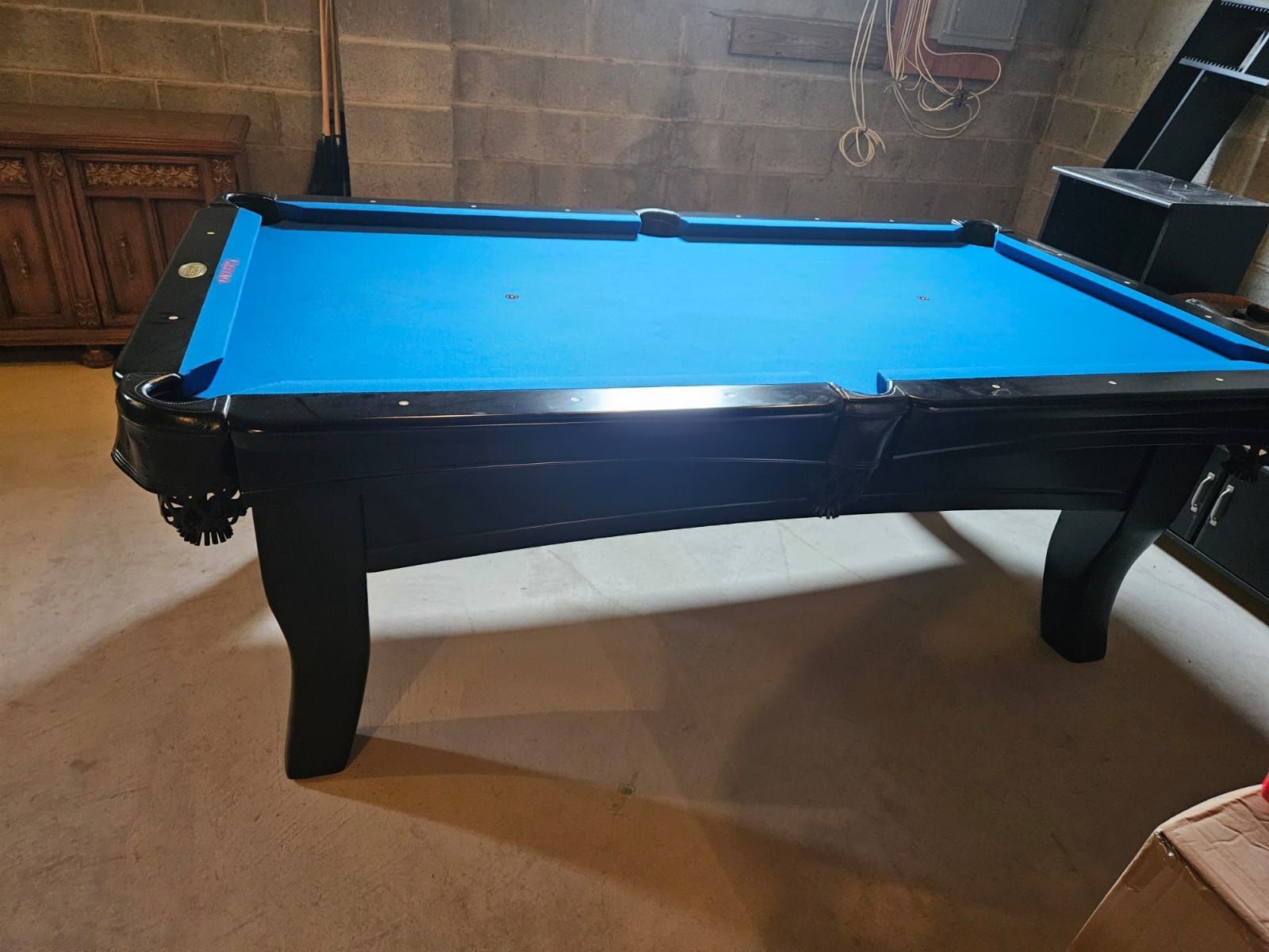 A pool table with a blue cloth is sitting in a room.