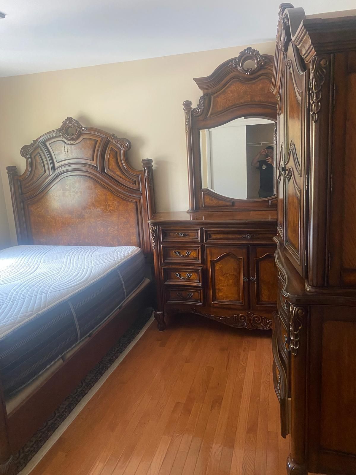 A bedroom with a bed , dresser , mirror and nightstand.