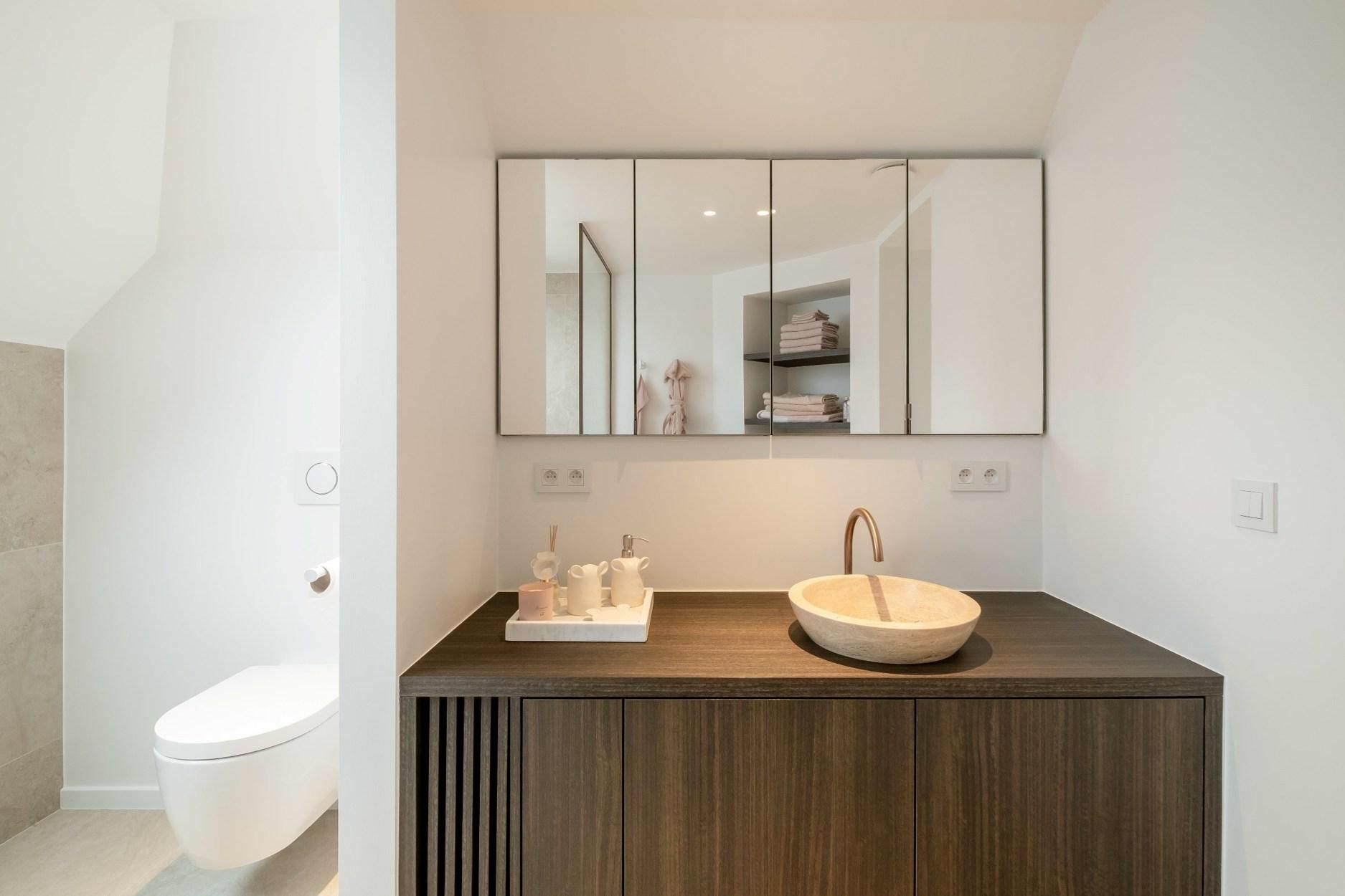 Een badkamer met wastafel, toilet en spiegel.