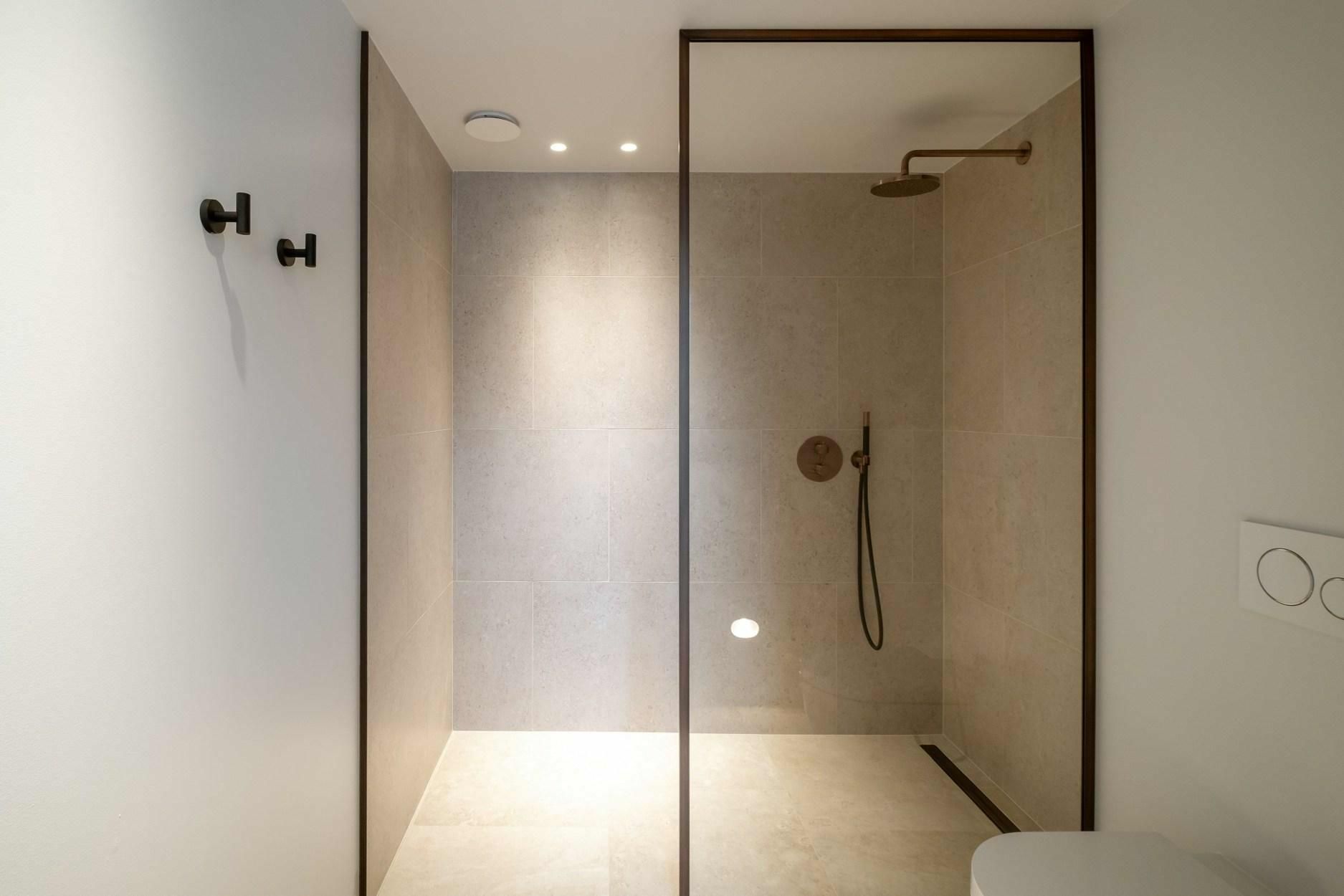 Een badkamer met inloopdouche en toilet.