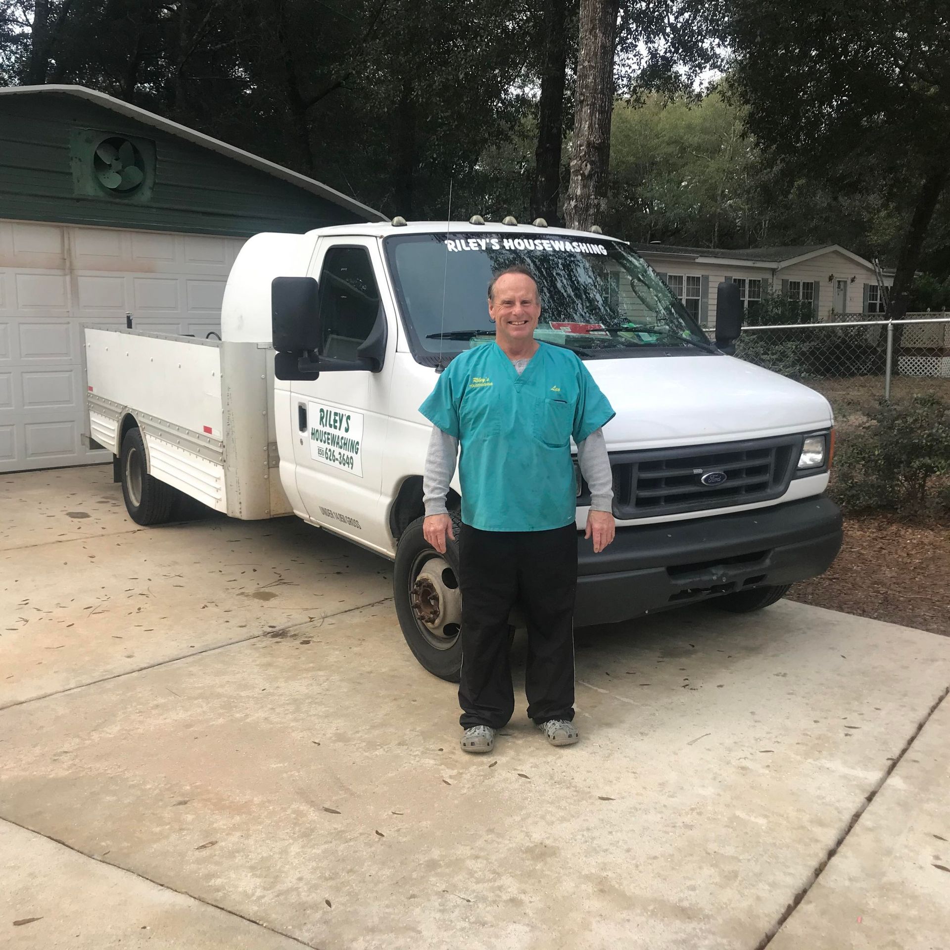A man in a scrub top is standing in front of a white truck.