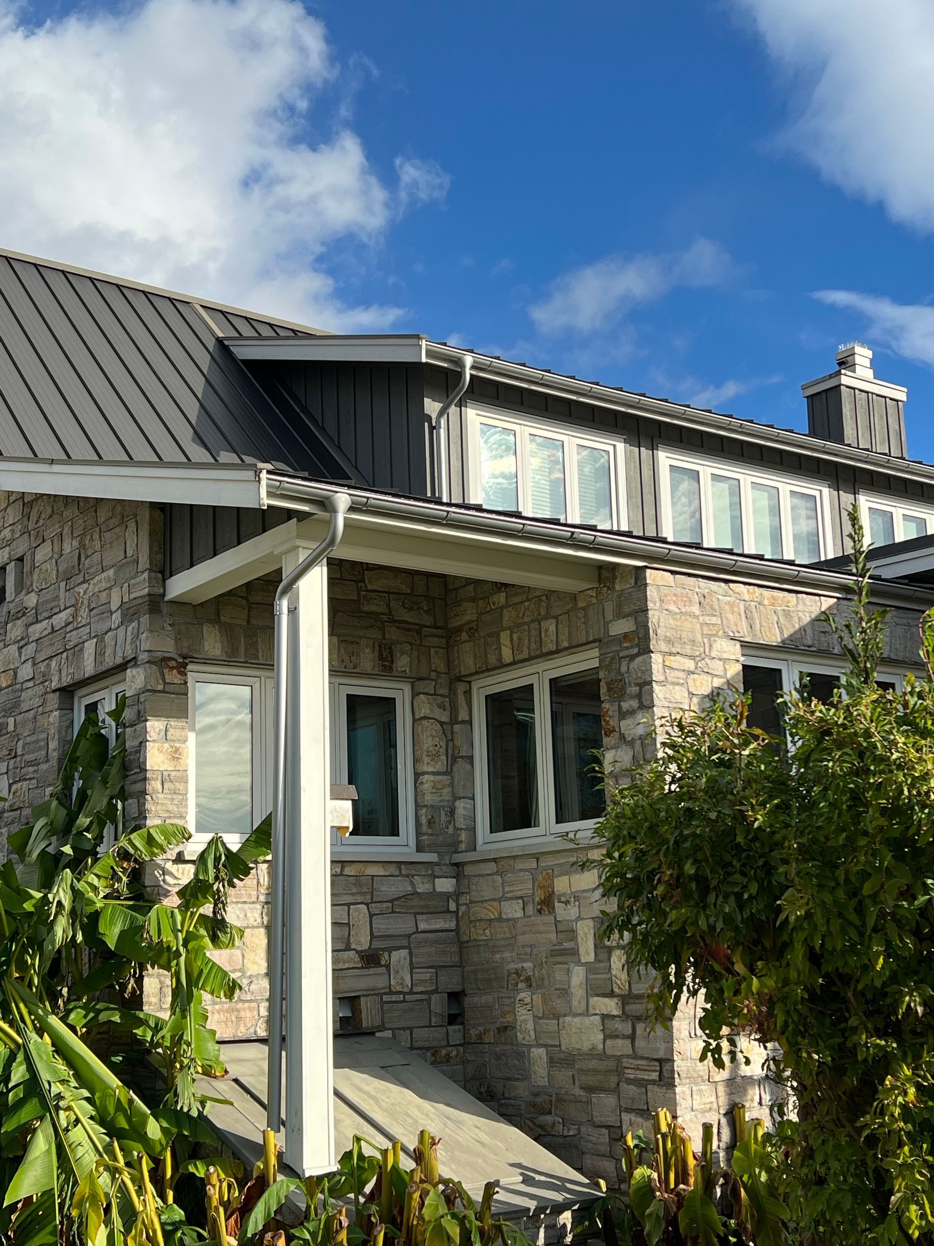 A stone house with a metal roof and a porch