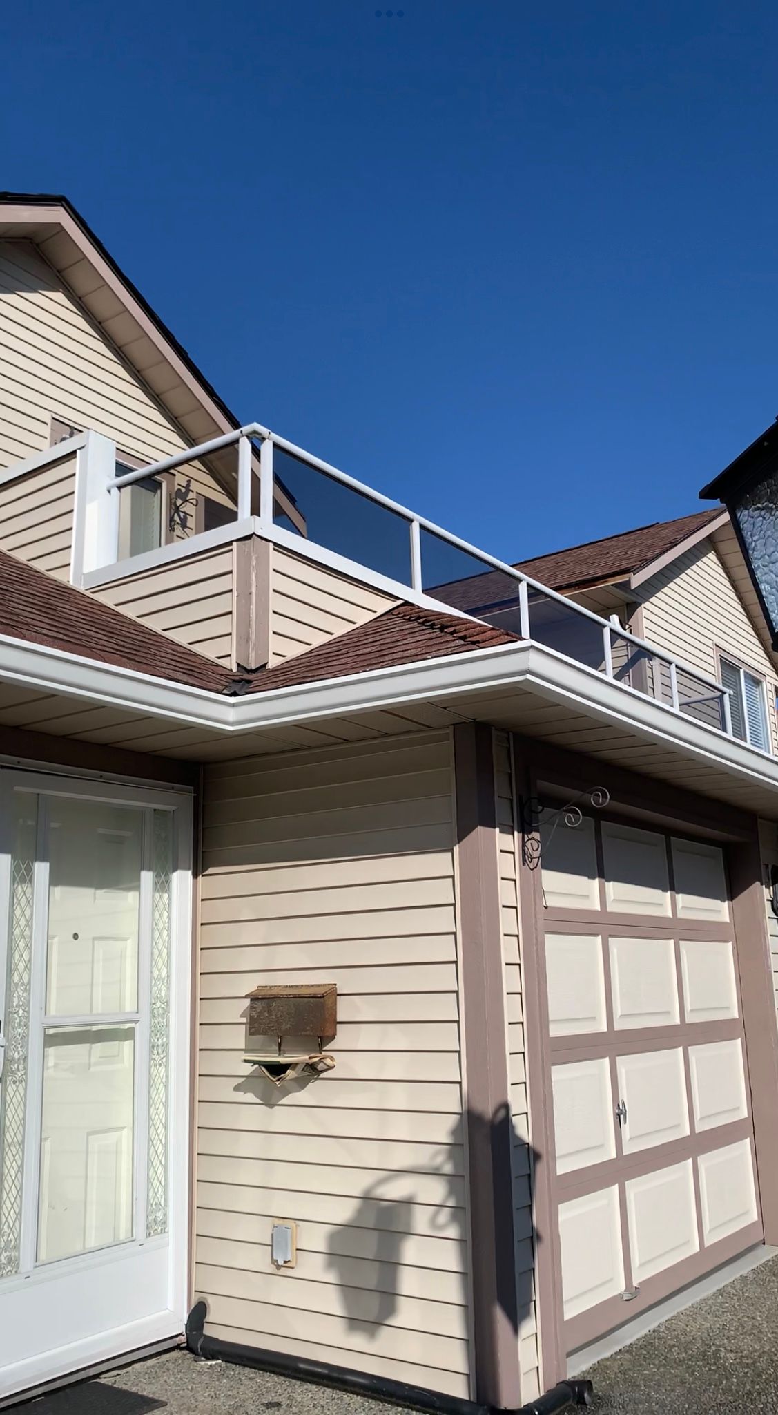A house with a garage and a balcony on top of it.