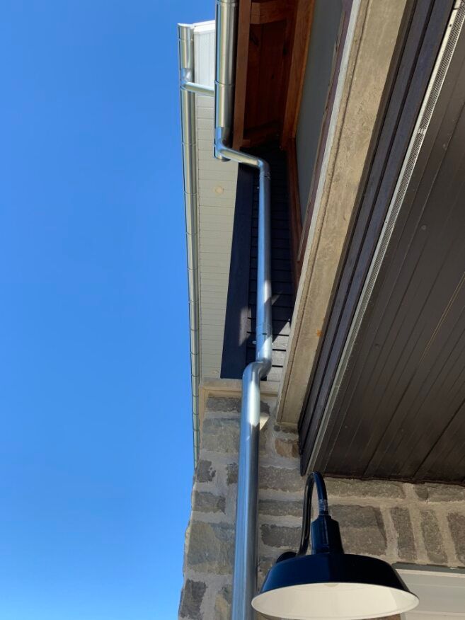 A black light is hanging from the side of a building next to a gutter.