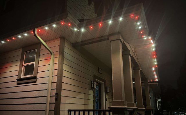 A house with christmas lights on the porch at night.