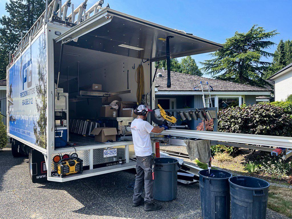 A man is working on a piece of wood in front of a truck.
